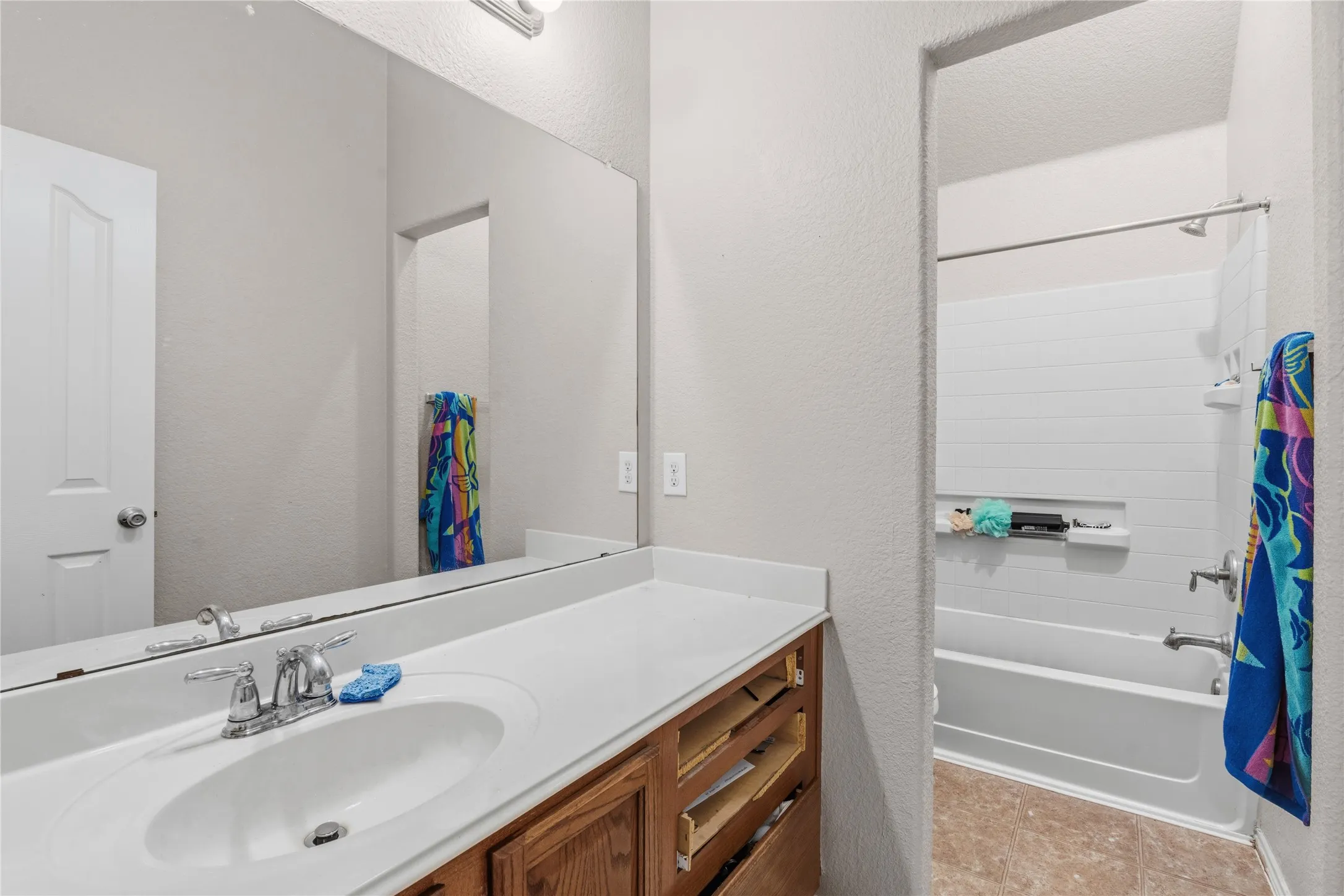 Bathroom featuring a single-sink vanity with wood-finish cabinetry, a white countertop, and a large wall-mounted mirror