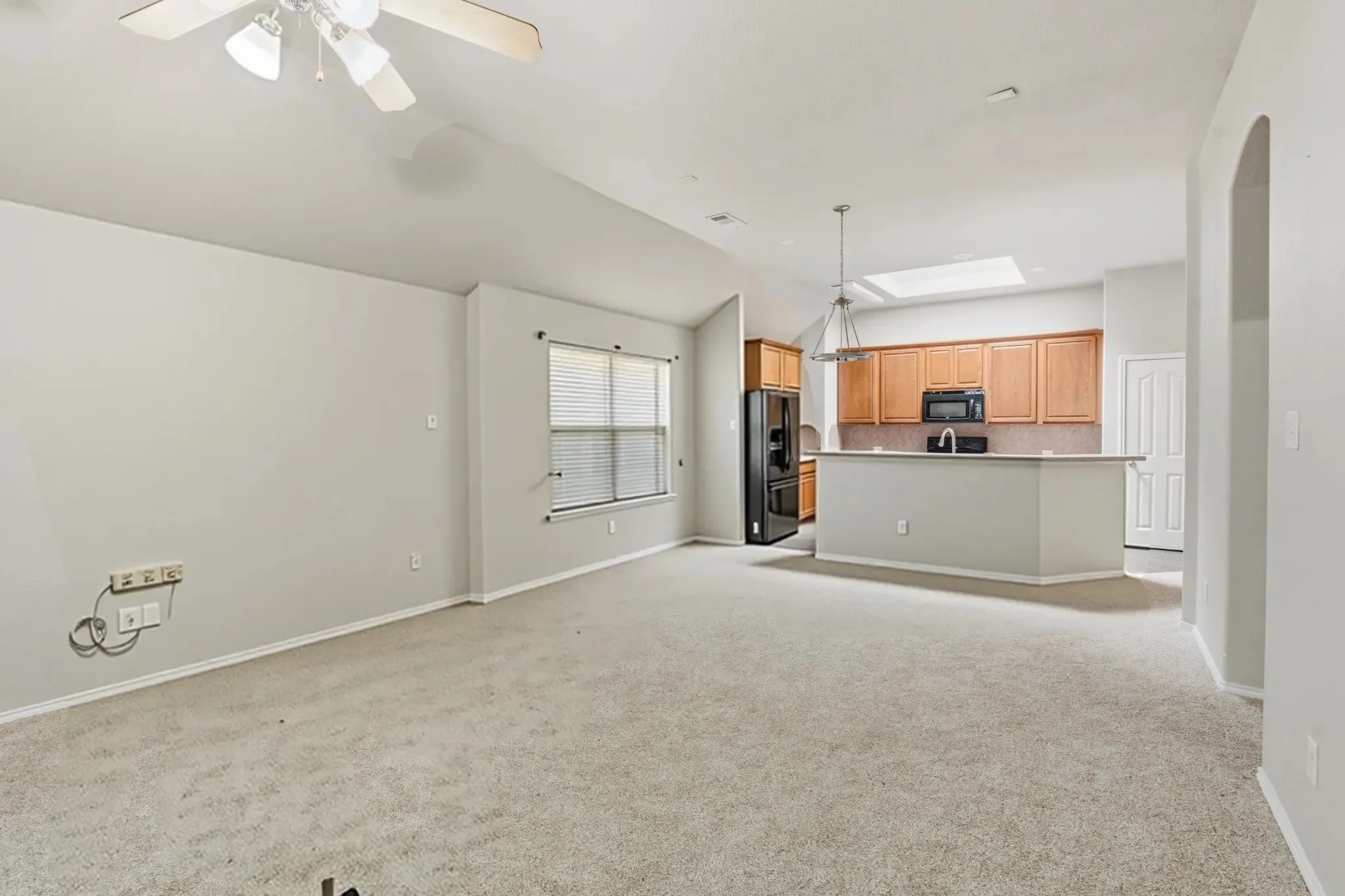 Open-concept living space featuring carpet flooring and a ceiling fan