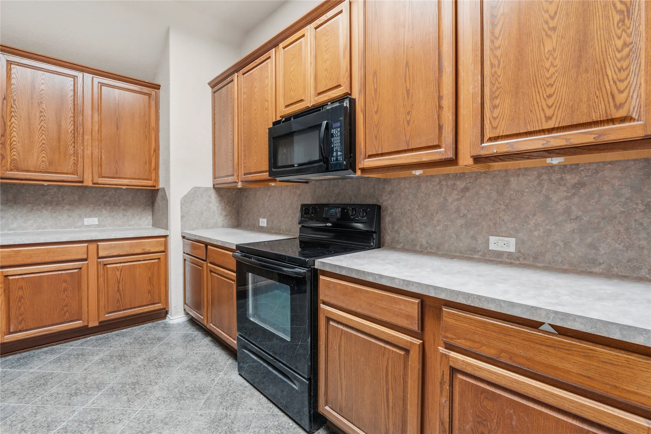 Kitchen featuring extensive wood cabinetry, black oven range, built-in microwave, and solid surface countertops with integrated backsplash