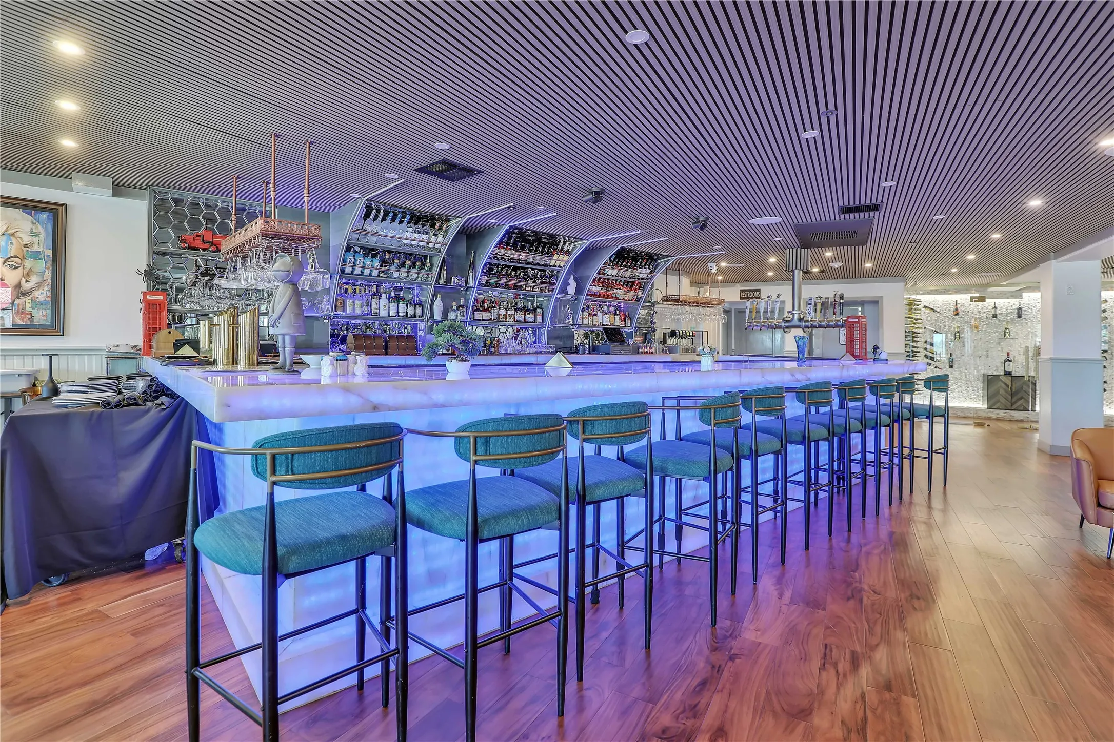 Illuminated bar area featuring a light-colored countertop and a series of barstools