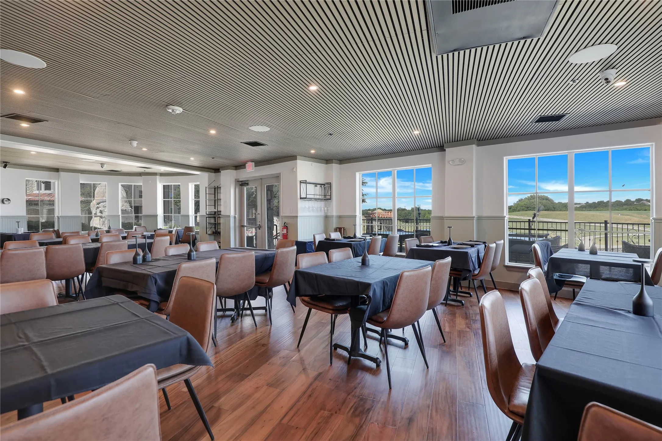 Spacious dining area featuring wood-finish flooring, a slatted ceiling, and expansive windows
