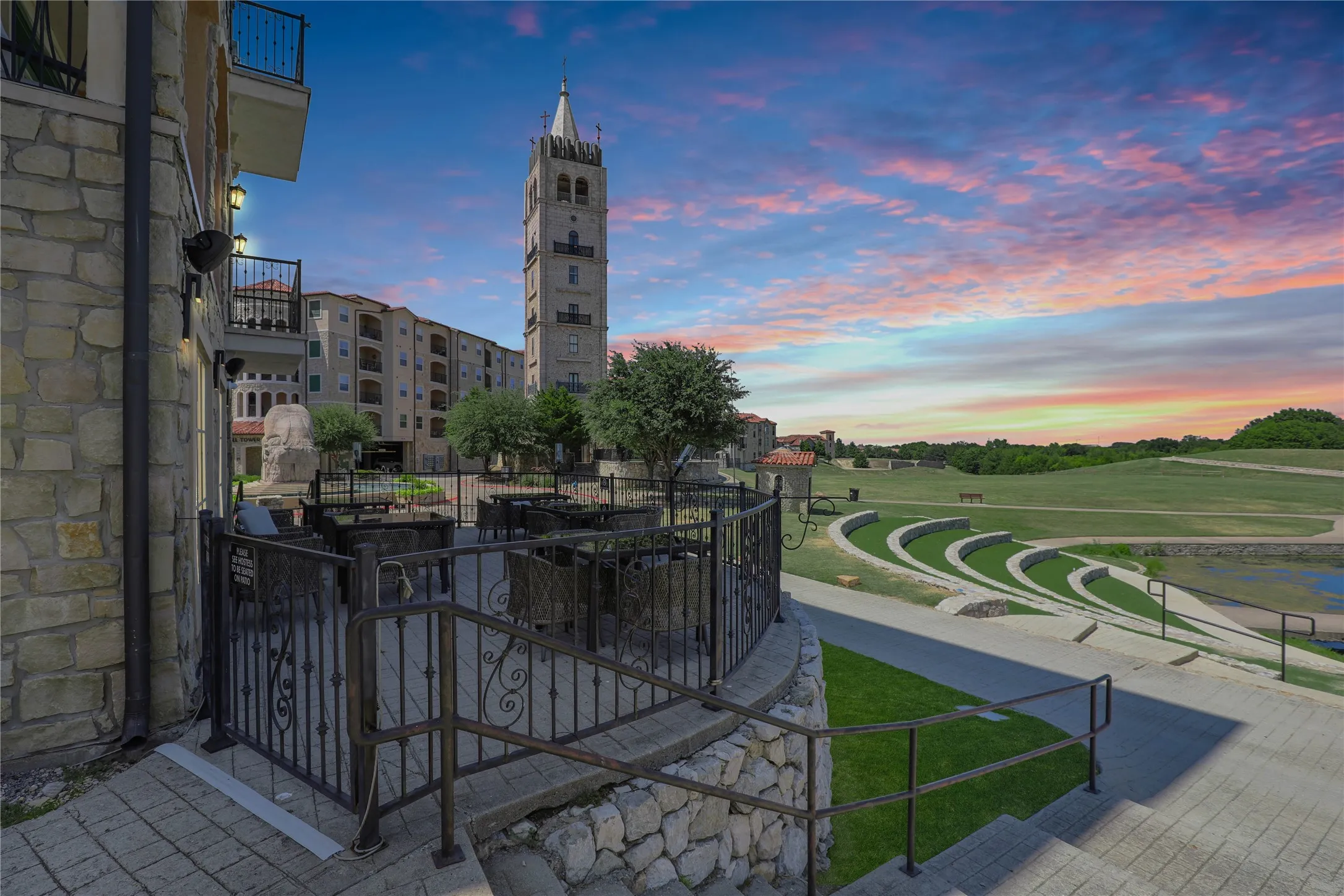 Patio area featuring stone walls, wrought iron railings, and a prominent bell tower