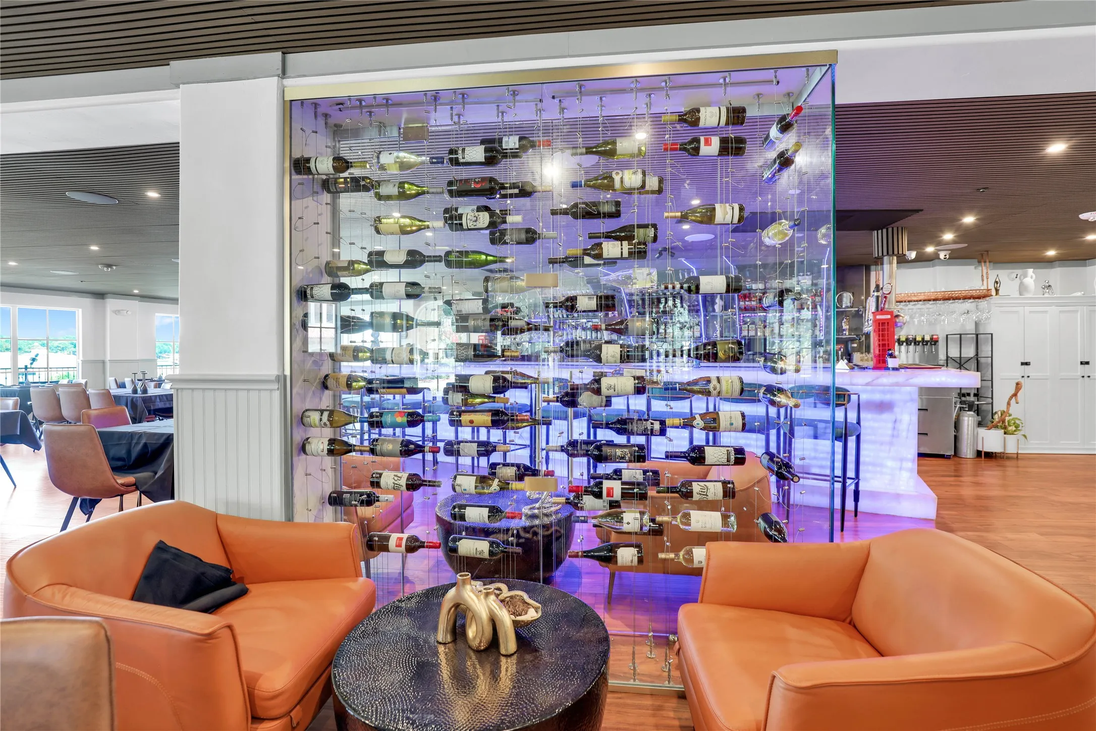 Custom glass wine wall with backlighting, hardwood-style flooring, white wainscoting, and recessed lighting