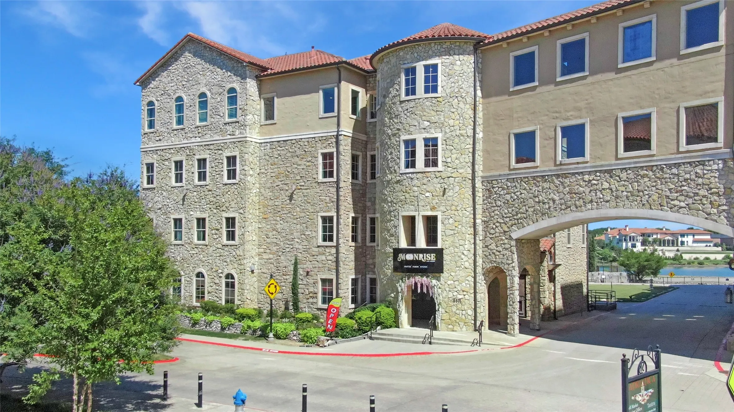 Multi-story building featuring stone and stucco exterior, arched windows, and a terracotta tile roof