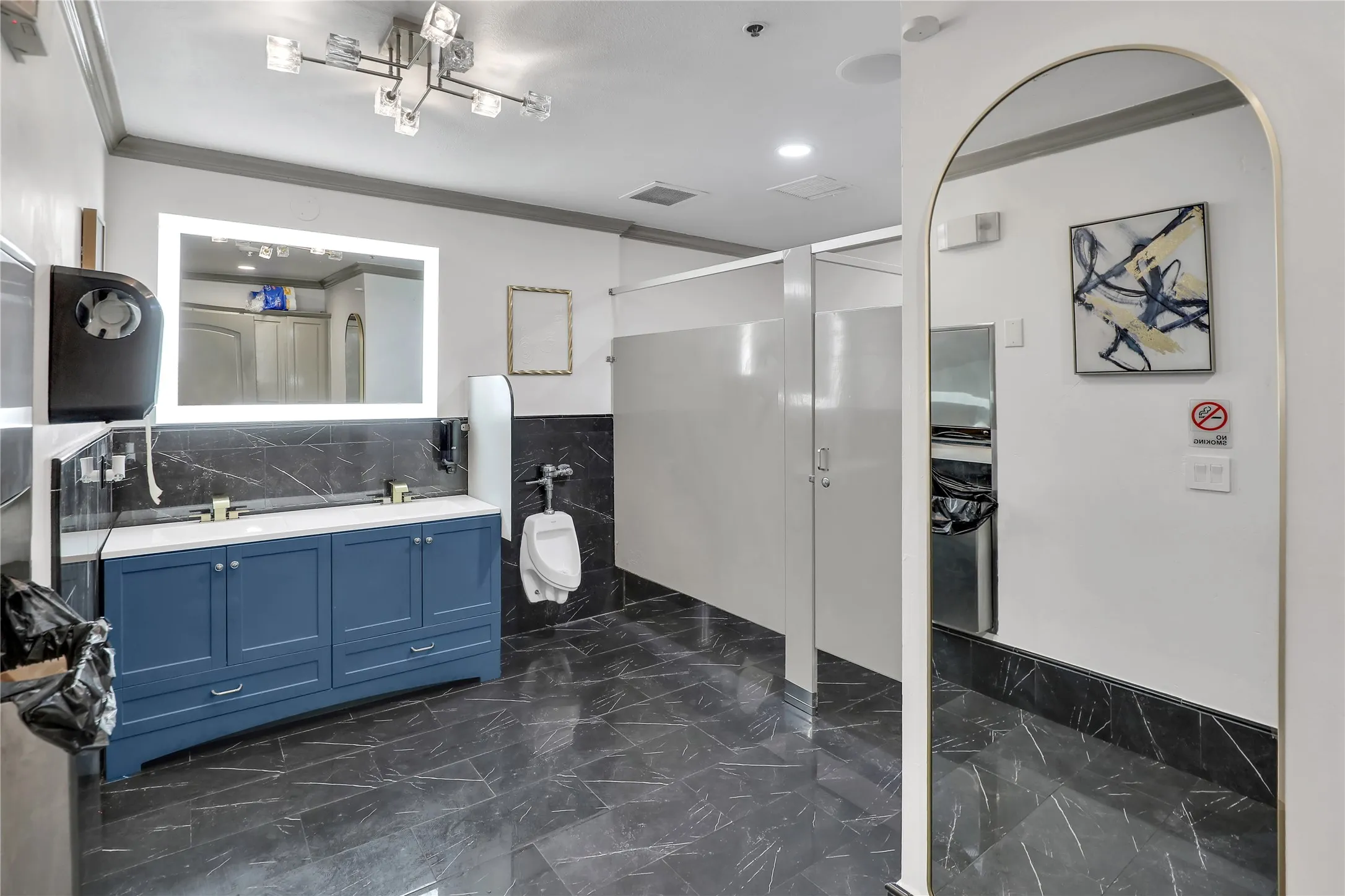 Spacious restroom featuring dual vanity with blue cabinetry, white countertops, and gold-finish faucets