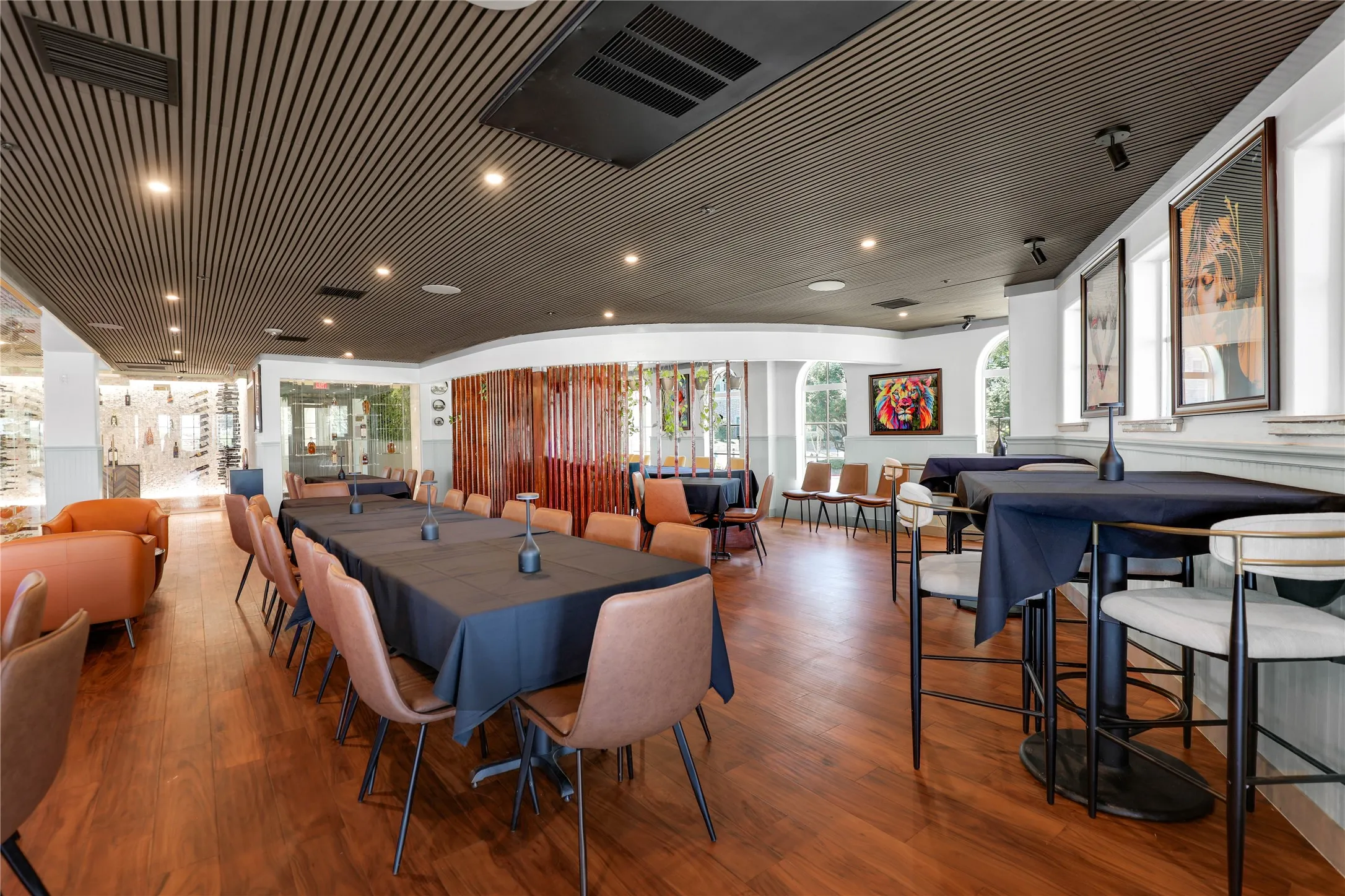 Spacious dining area featuring wood-finish flooring, a slatted ceiling, recessed lighting, and arched windows