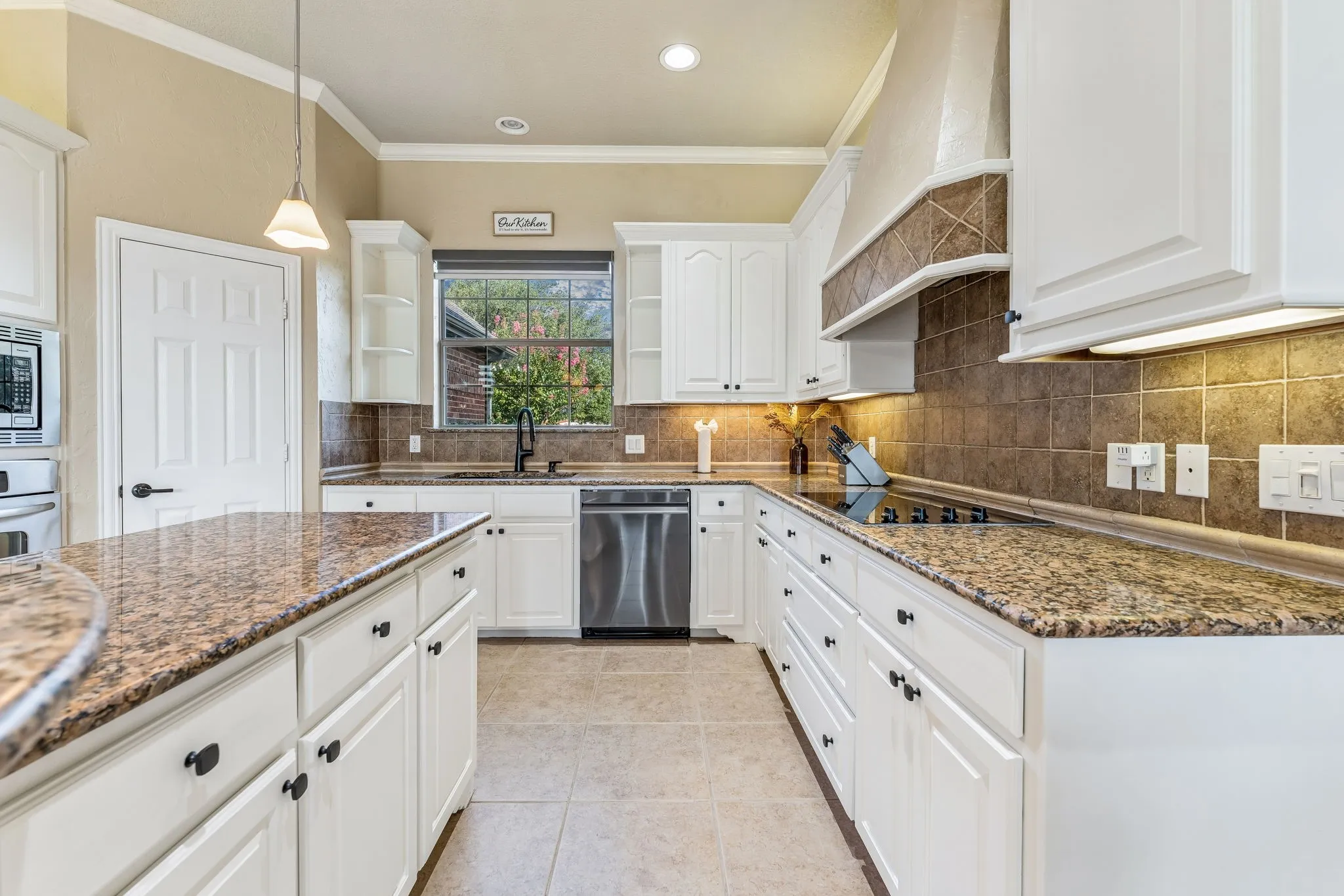 Kitchen with electric cook top, view of the front yard,  island and pantry.