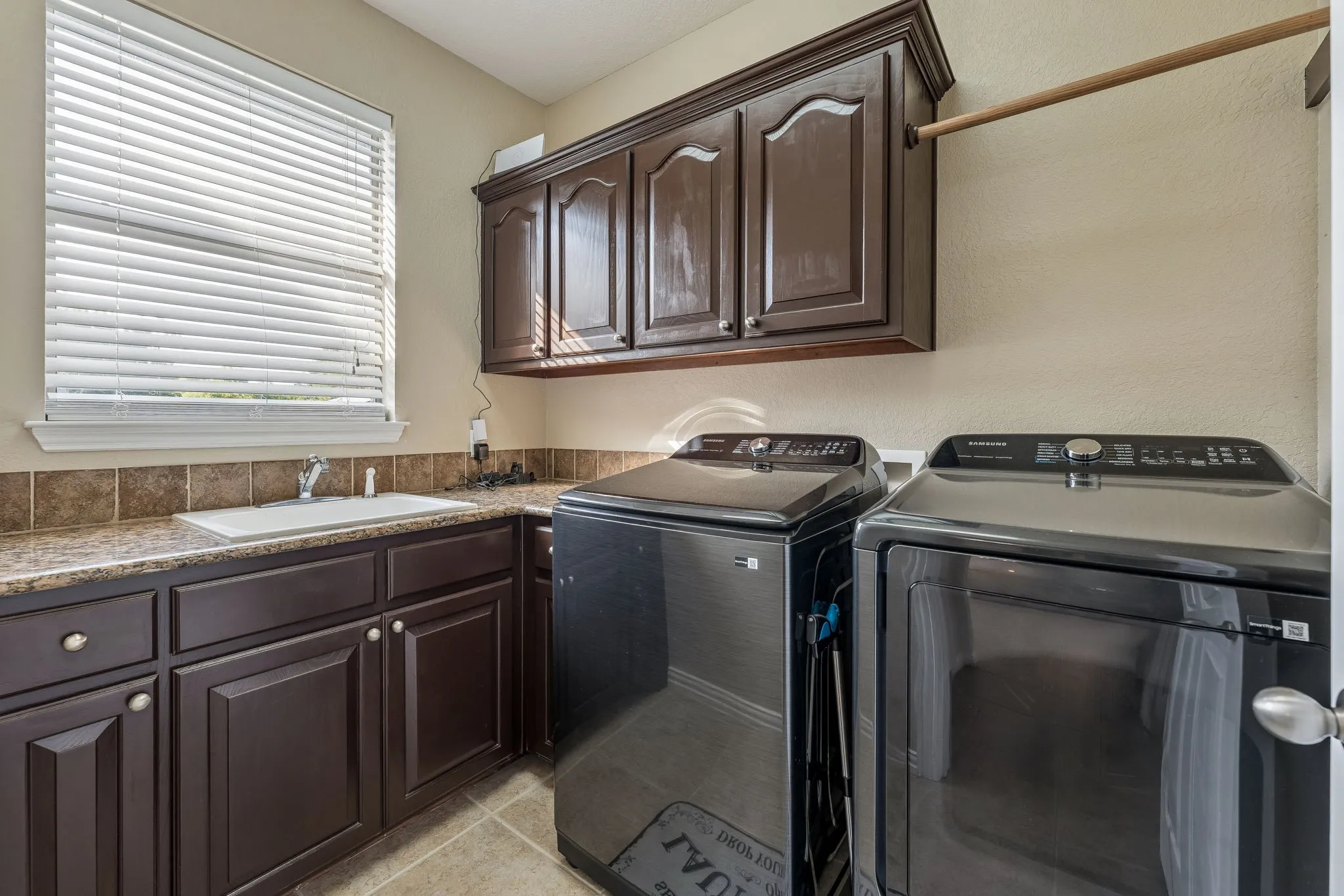 Laundry room with full size washer and dryer and sink with cabinets for storage.