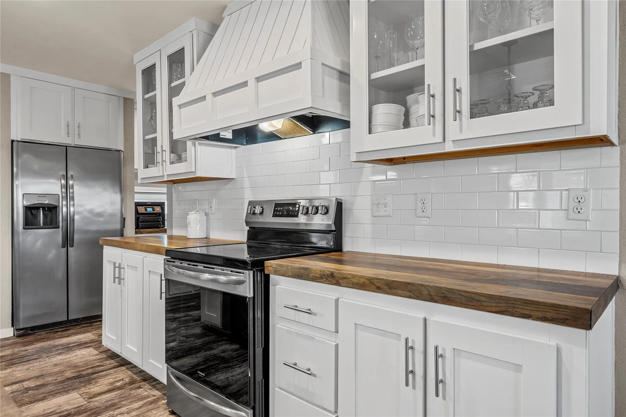 Modern kitchen featuring white cabinetry, wood-finish countertops, and a white subway tile backsplash