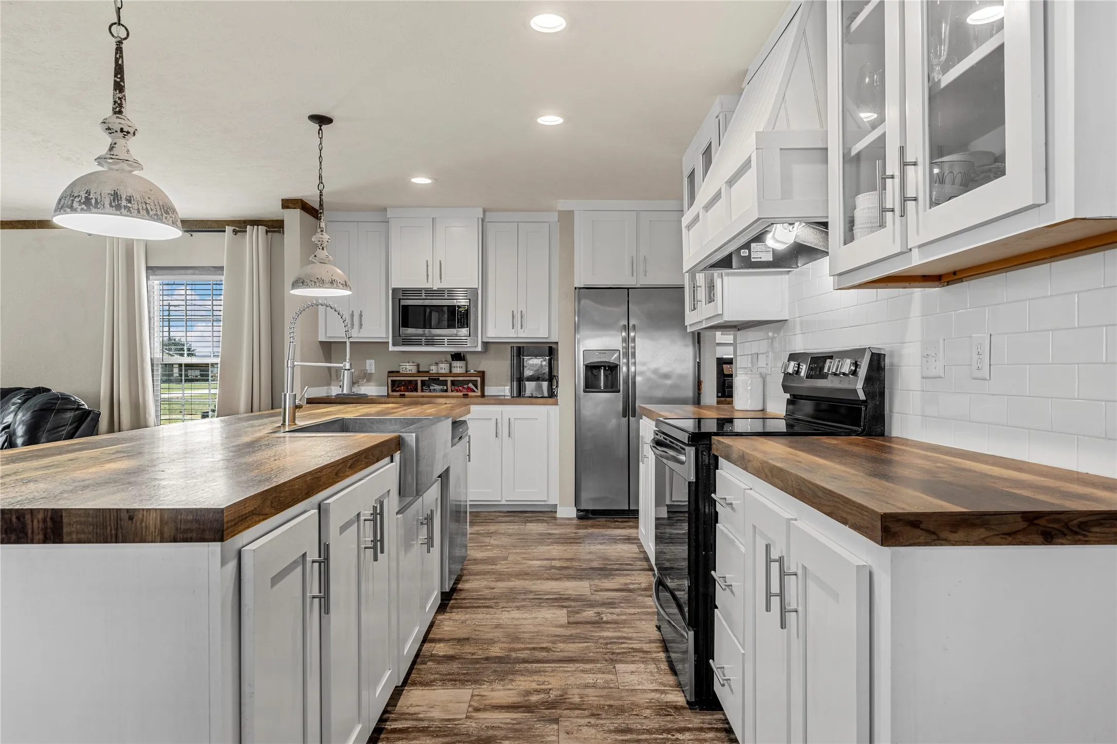 Kitchen featuring white cabinetry, wood-finish countertops, subway tile backsplash, stainless steel appliances, and wood-finish flooring