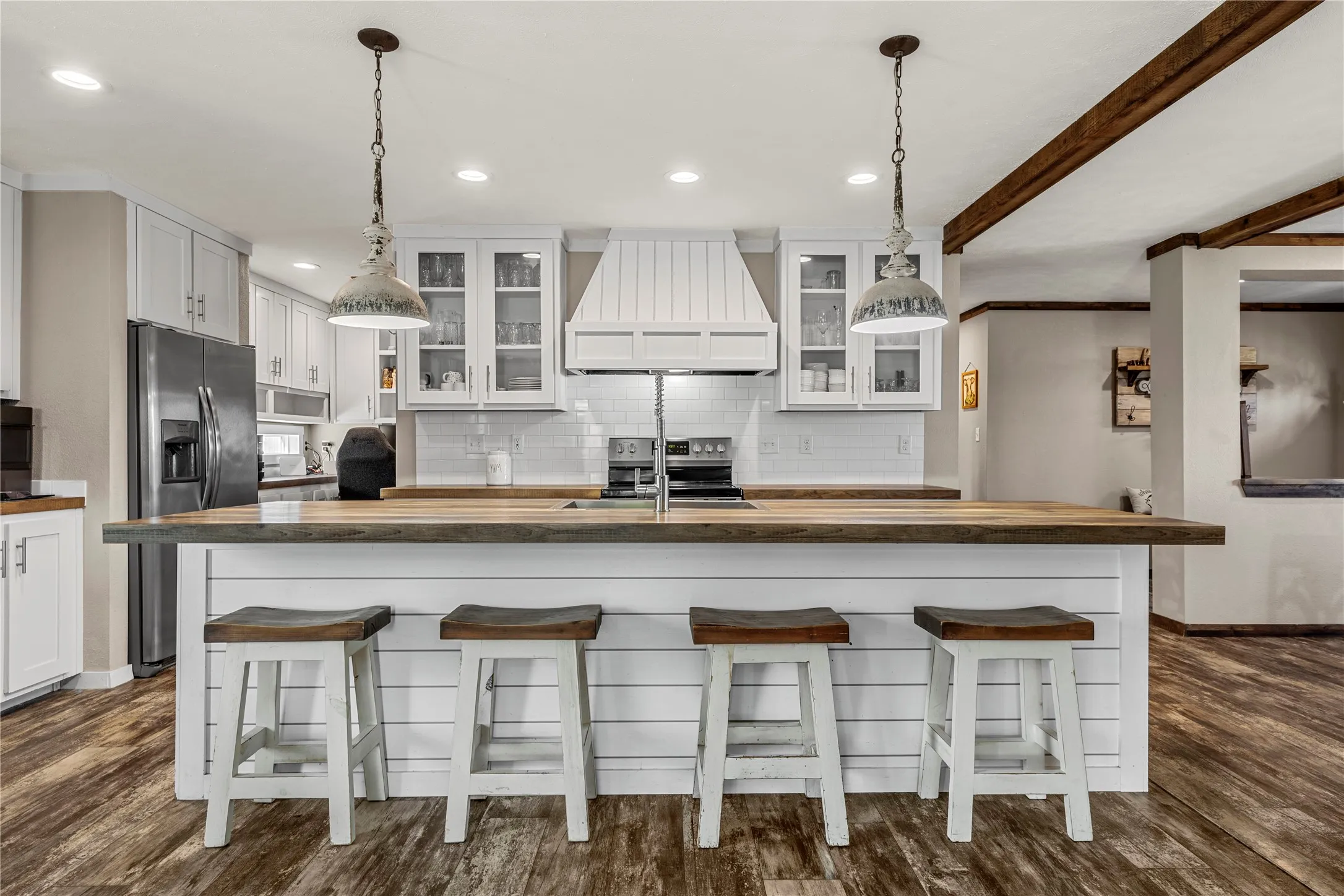 Kitchen featuring a large island with wood-finish countertop, white shiplap base, and pendant lighting
