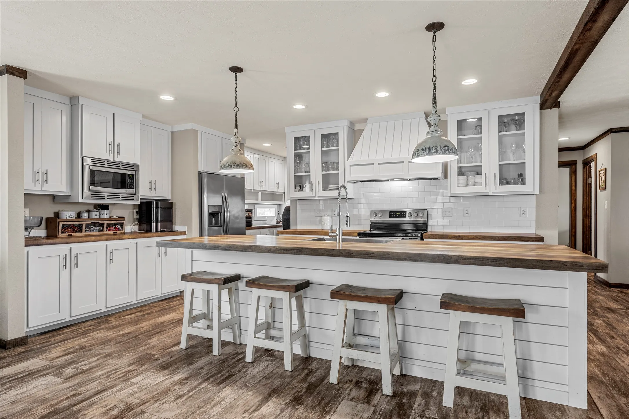 Spacious kitchen featuring an island with wood-finish countertop, white shiplap base, and pendant lighting