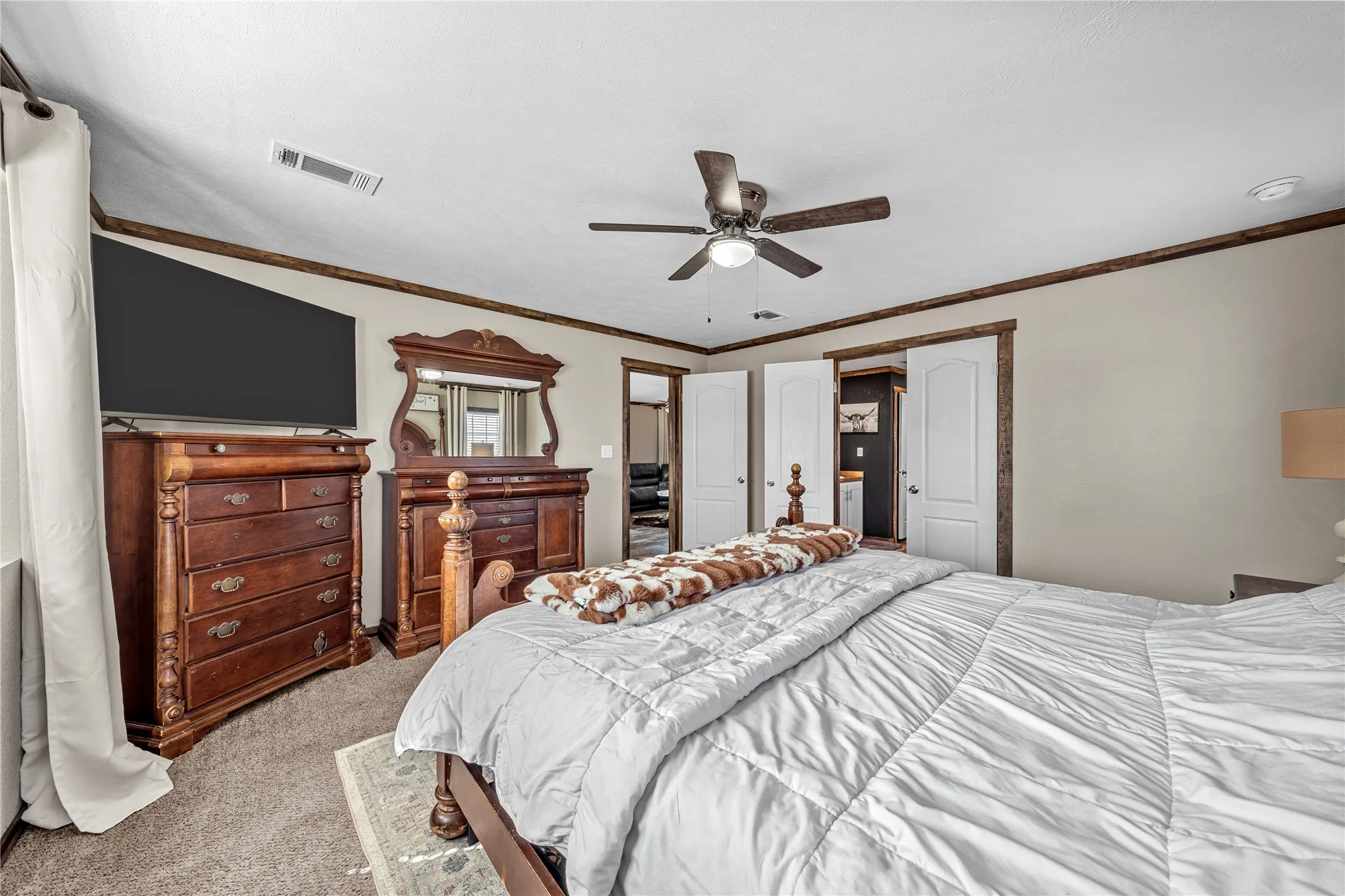 Spacious bedroom featuring neutral wall tones, a ceiling fan with integrated lighting, and carpeted flooring