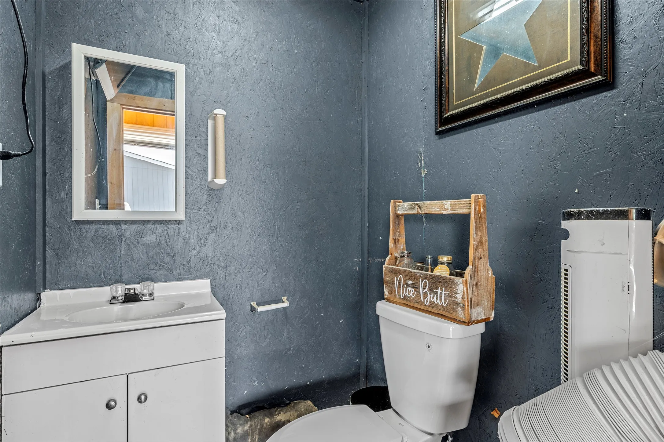 Corner vanity with integrated sink, wall-mounted mirror, and wall-mounted light fixture