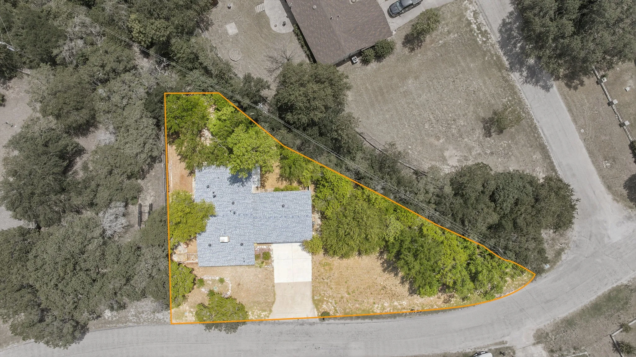 Property parcel featuring a gray shingle roof, concrete driveway, and mature landscaping