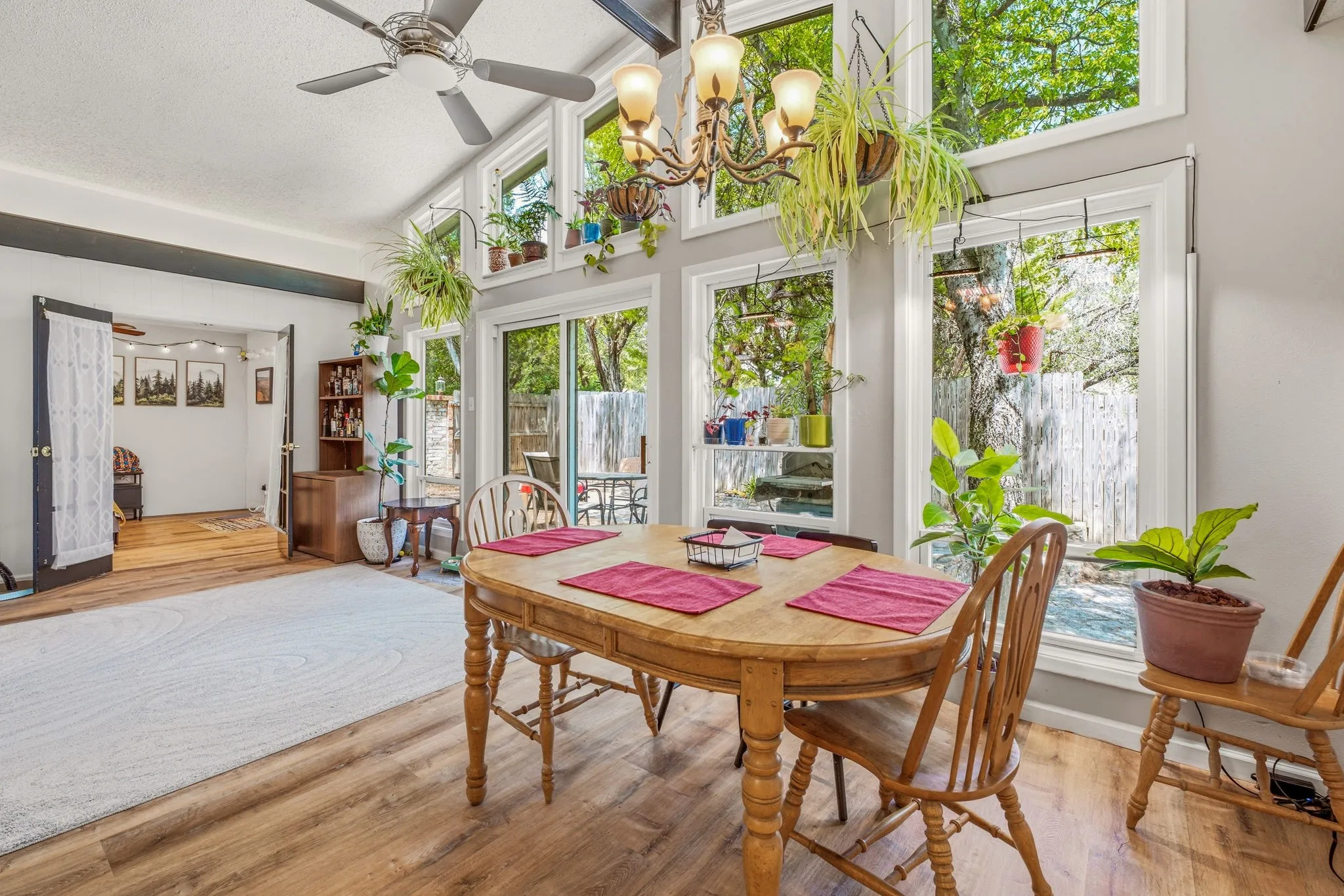 Dining area featuring a vaulted ceiling with a fan and chandelier, wood-finish flooring, and expansive windows