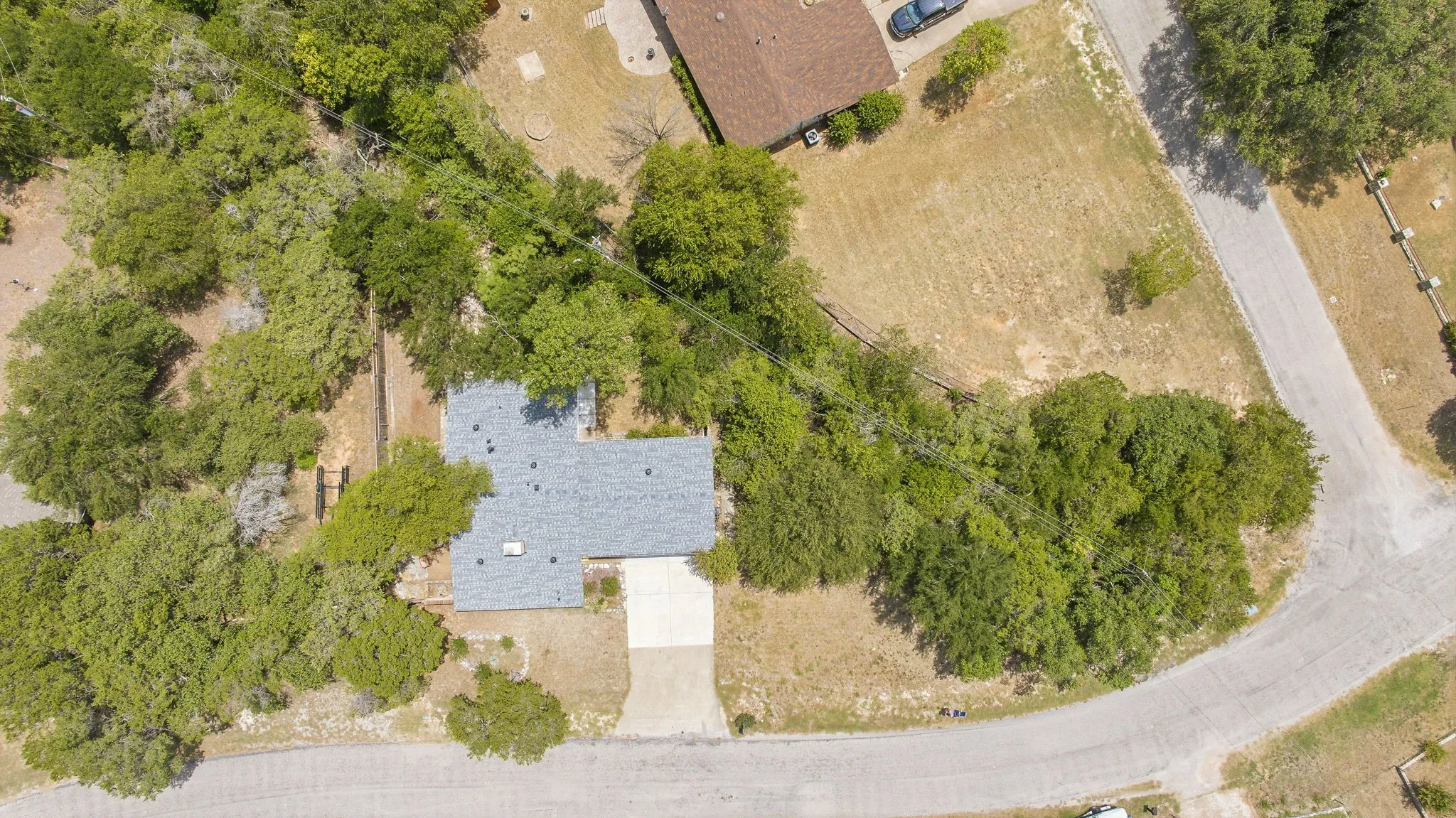 Single-story residence with a gray shingle roof, surrounded by mature trees
