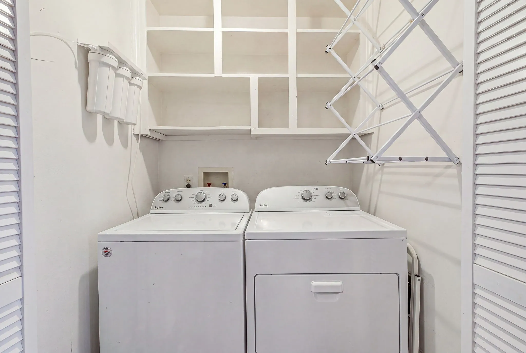 Dedicated laundry area featuring a white washing machine, white dryer, built-in shelving, and a wall-mounted drying rack