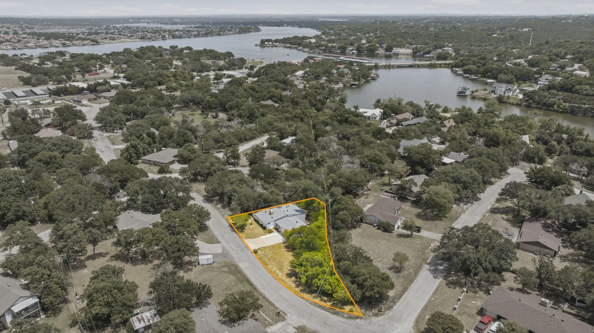 Aerial perspective showcasing a property with mature trees and a paved driveway, positioned on a corner lot