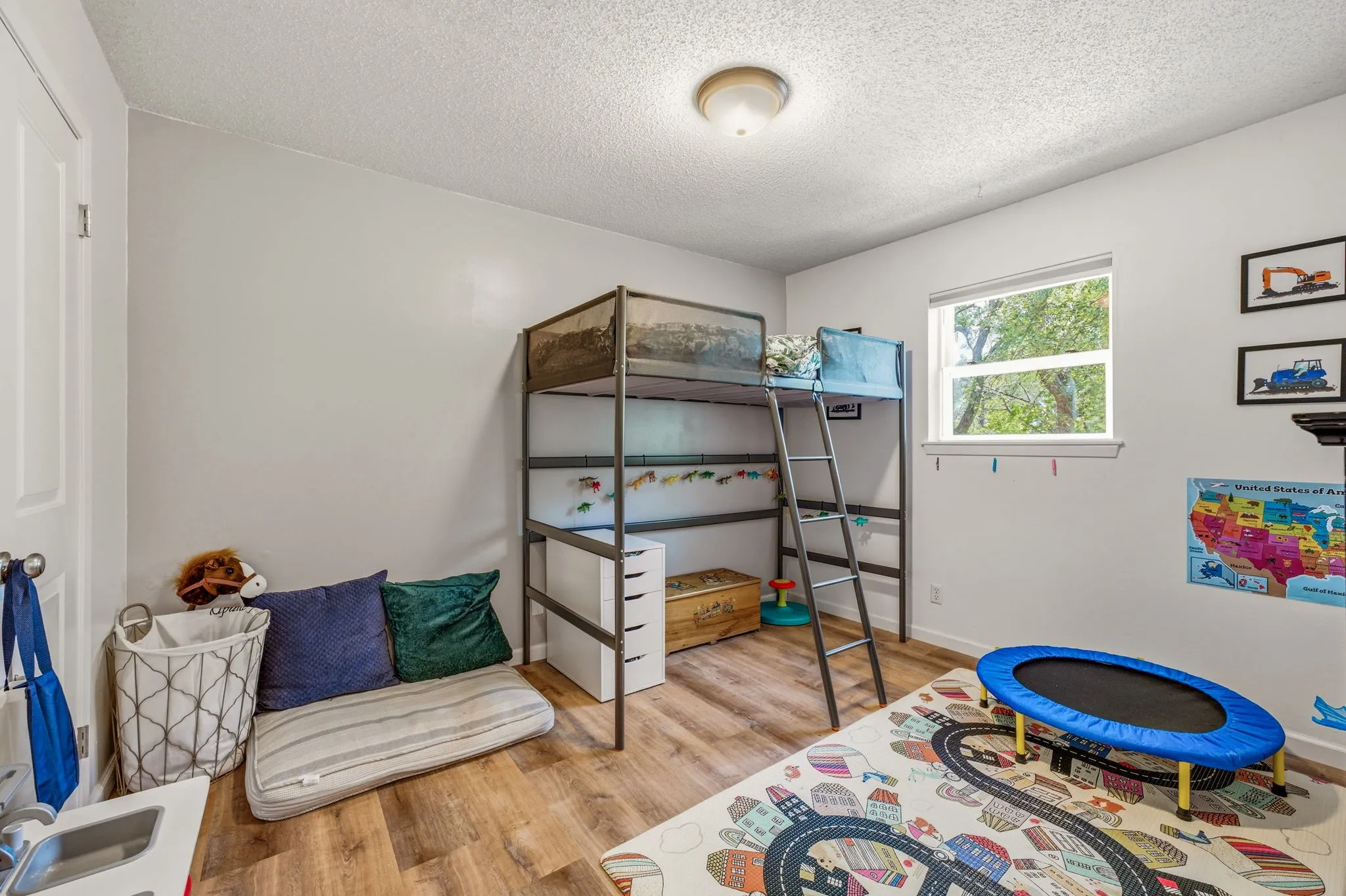 Room featuring wood-finish flooring, a window with natural light, textured ceiling, and a flush-mount ceiling light fixture