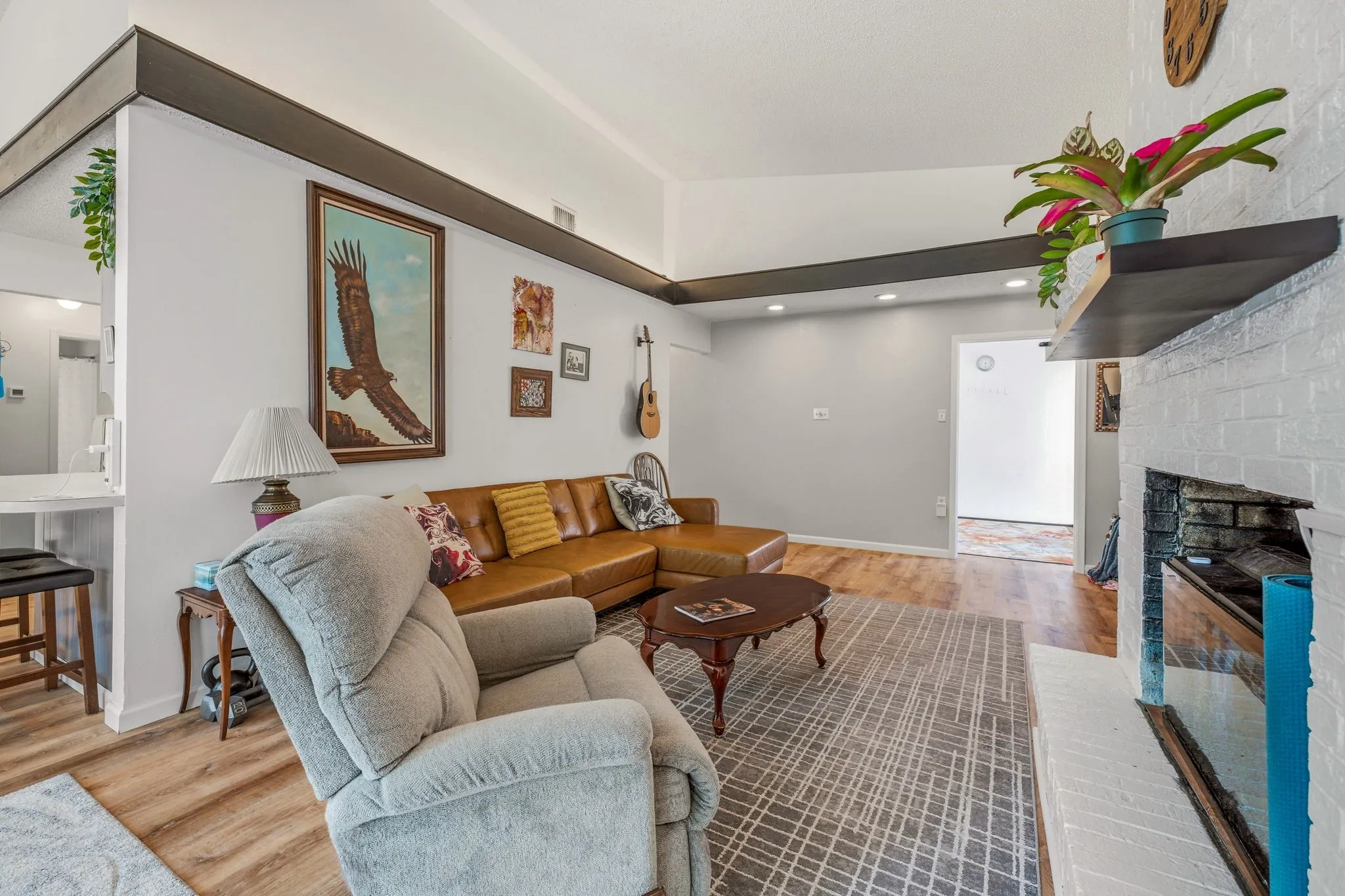 Living area featuring a vaulted ceiling with exposed beams, wood-finish flooring, and recessed lighting