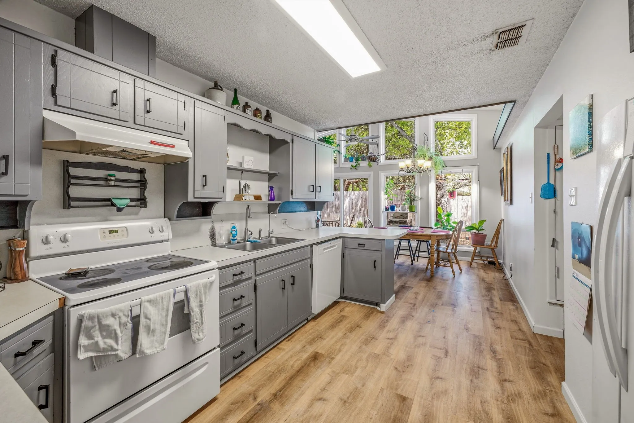 Kitchen featuring wood-finish flooring, gray cabinetry, white countertops, and white appliances