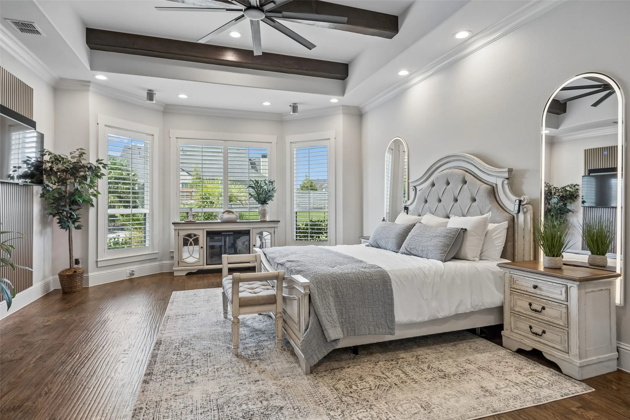 A Spacious Primary Retreat – The primary bedroom offers generous proportions, hand-scraped hardwood floors, a tray ceiling with exposed beams, and a bay of windows that brings in natural light and backyard views.