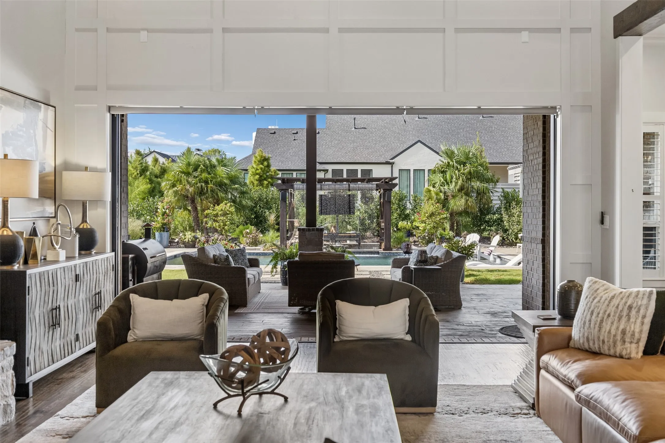 Indoor-Outdoor Living at Its Best – The great room opens directly to the covered terrace through a retracting wide glass wall, creating an easy flow between the kitchen, living area, outdoor seating, and pool.