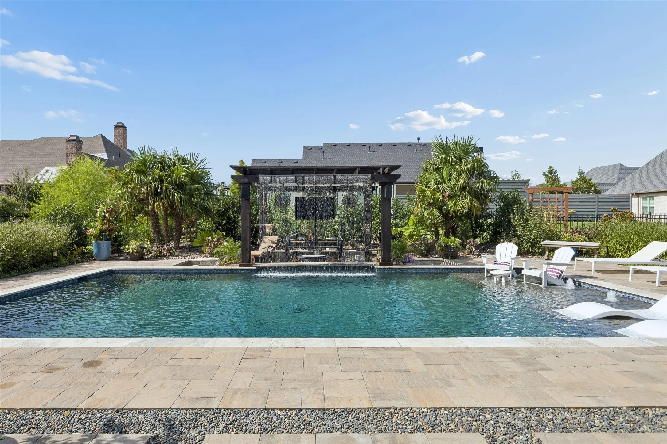 A Backyard Built Around Relaxation – The pool, pergola, sun shelf, and surrounding lounge areas create distinct places to swim, unwind, gather, or enjoy the garden setting.