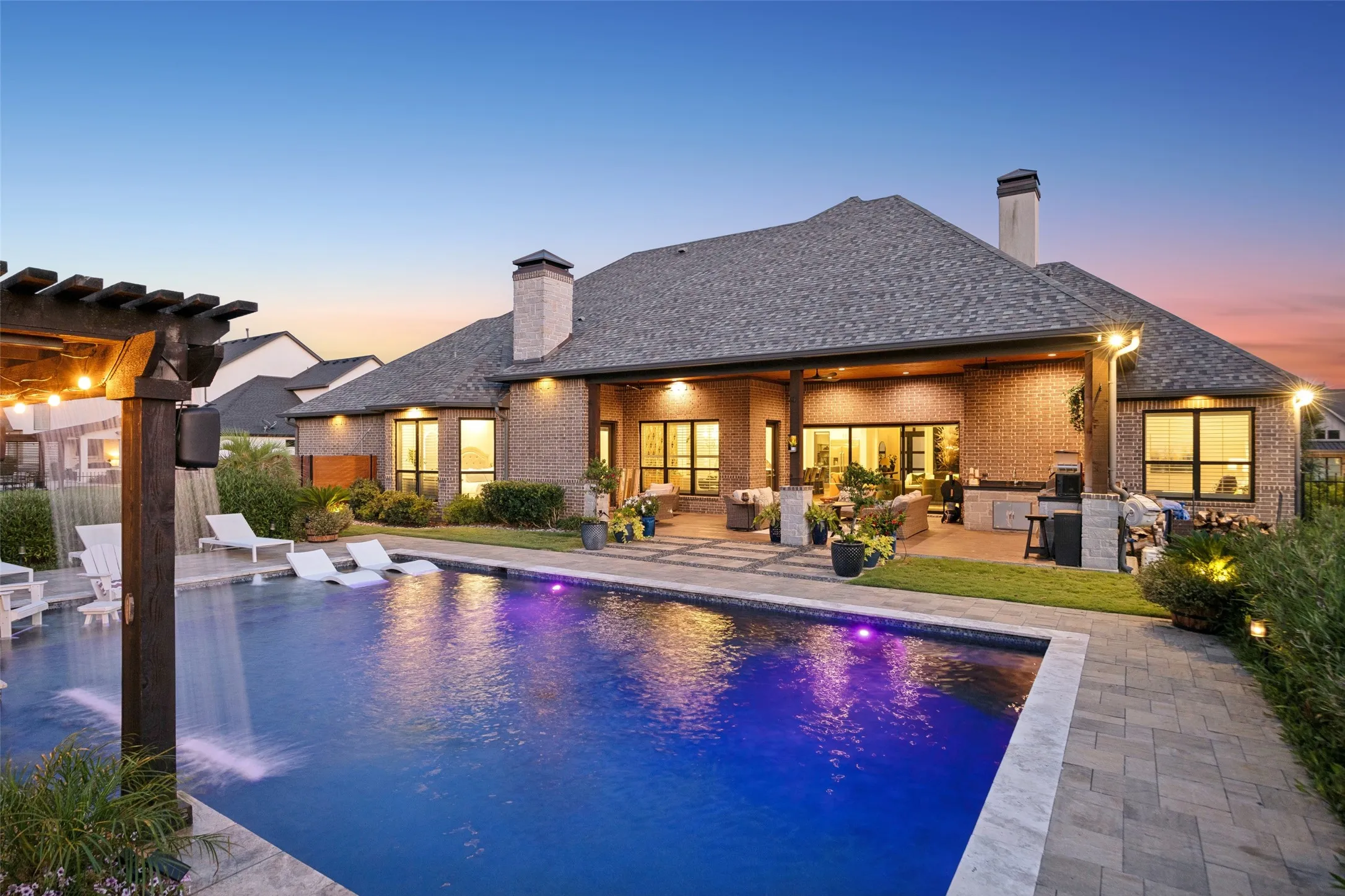 Resort-Style Living, Right at Home – The illuminated pool, covered outdoor living area, and expansive rear elevation create a striking evening setting designed for effortless entertaining and everyday relaxation.
