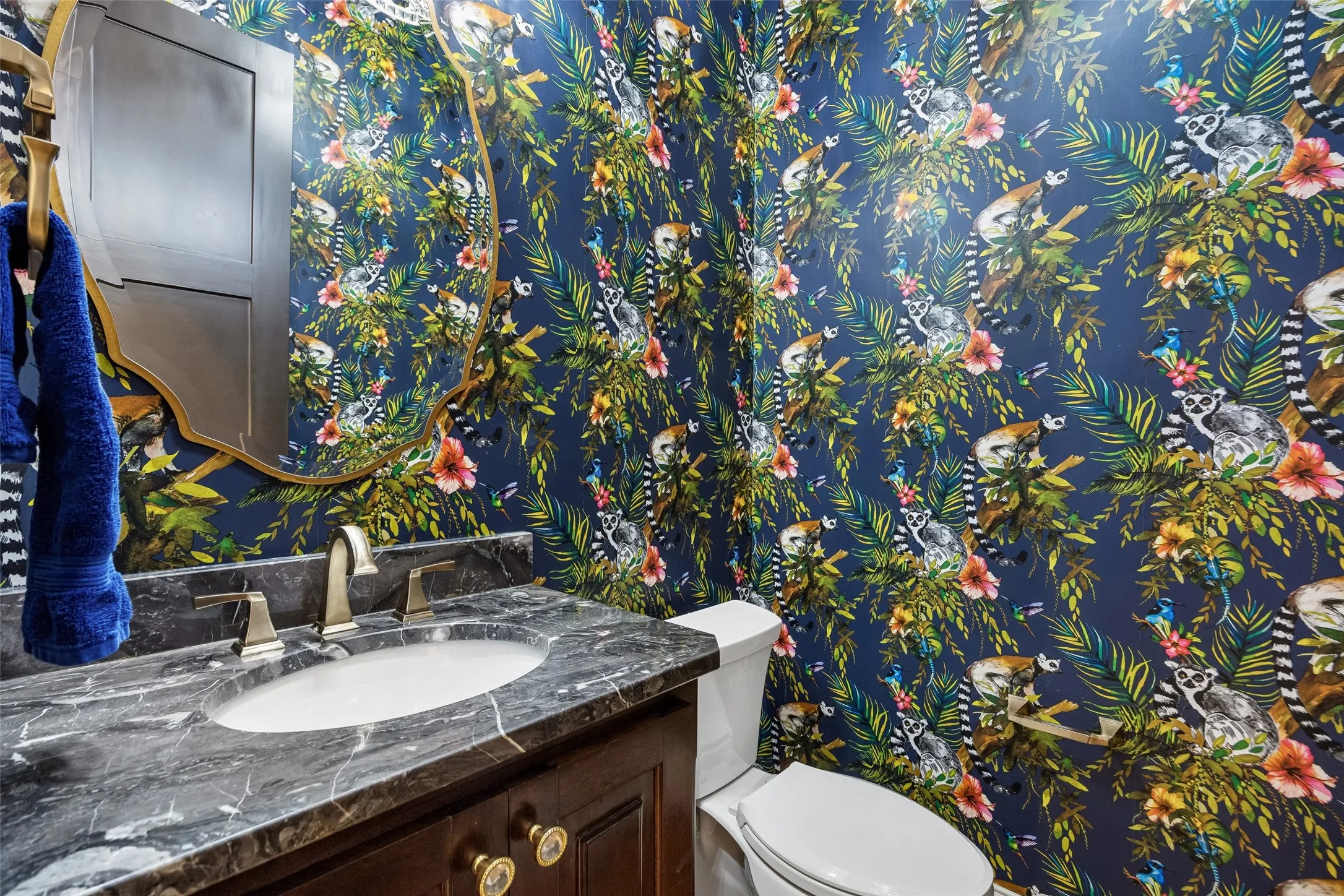 A Powder Bath with Personality – Every house needs a statement room and this one hits the market with bold wallpaper, a sculptural mirror, dark stone counter, and warm metal fixtures give this guest bath a memorable, custom-designed look.