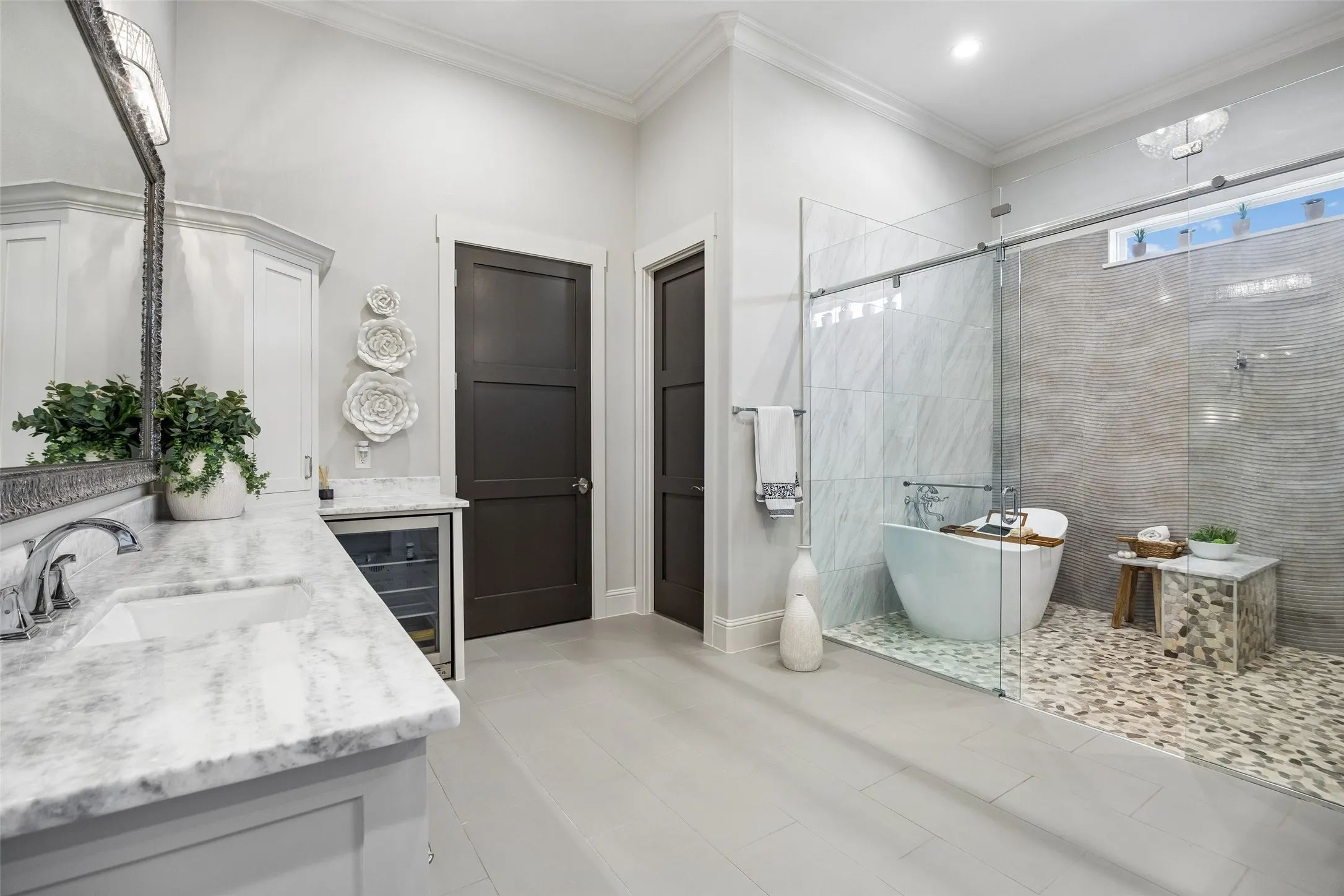A Spa-Inspired Wet Room – The primary bath features a glass-enclosed wet room with a freestanding soaking tub, multi-head shower, pebble flooring, textured tile, and natural light for a relaxing retreat at home.