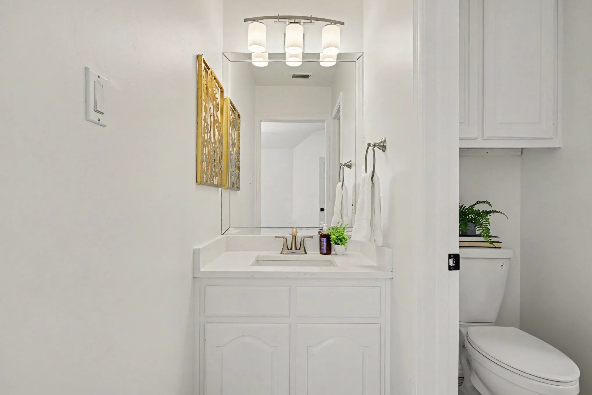Bright and functional bathroom featuring a white cabinetry vanity with dual drawers, integrated sink with brushed nickel faucet, and ample mirror with integrated lighting