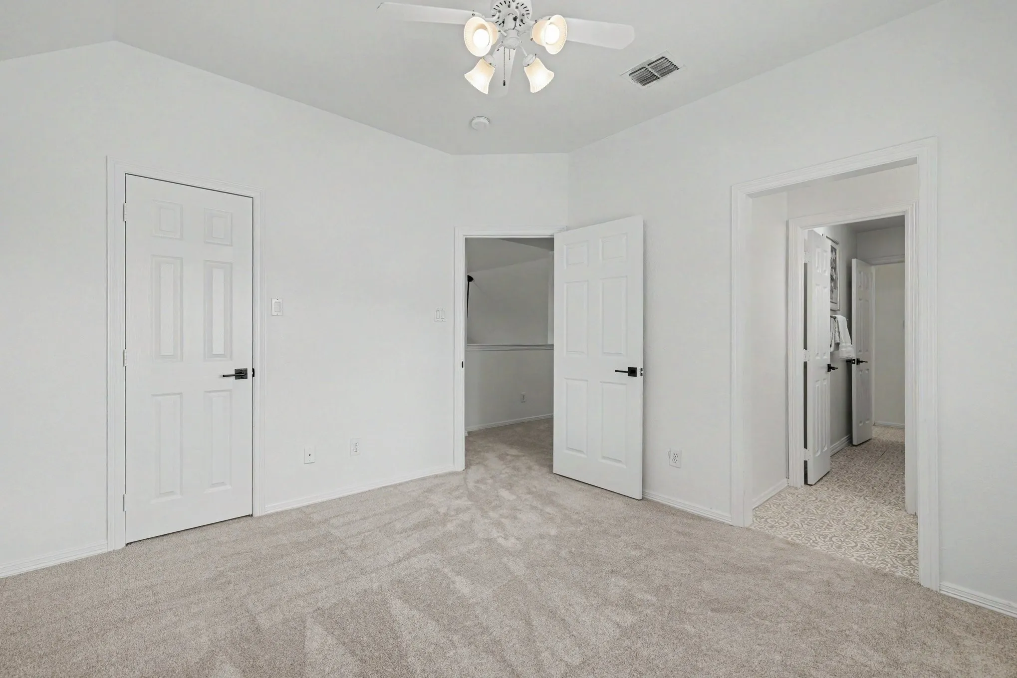 Interior room featuring light-toned carpeting, white walls, and a ceiling fan with integrated lighting