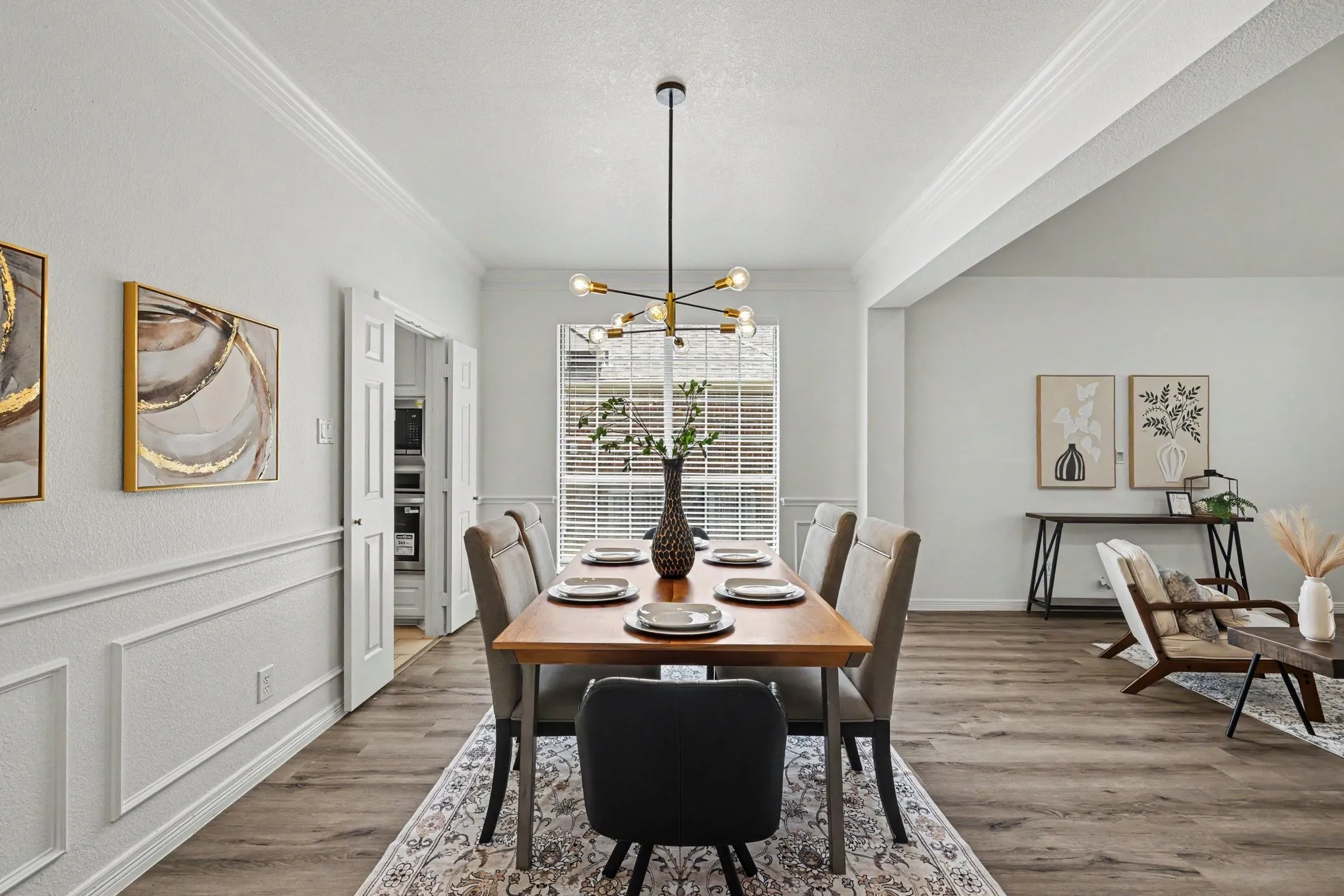 Dining space featuring wood-finish flooring, wainscoting, and crown molding