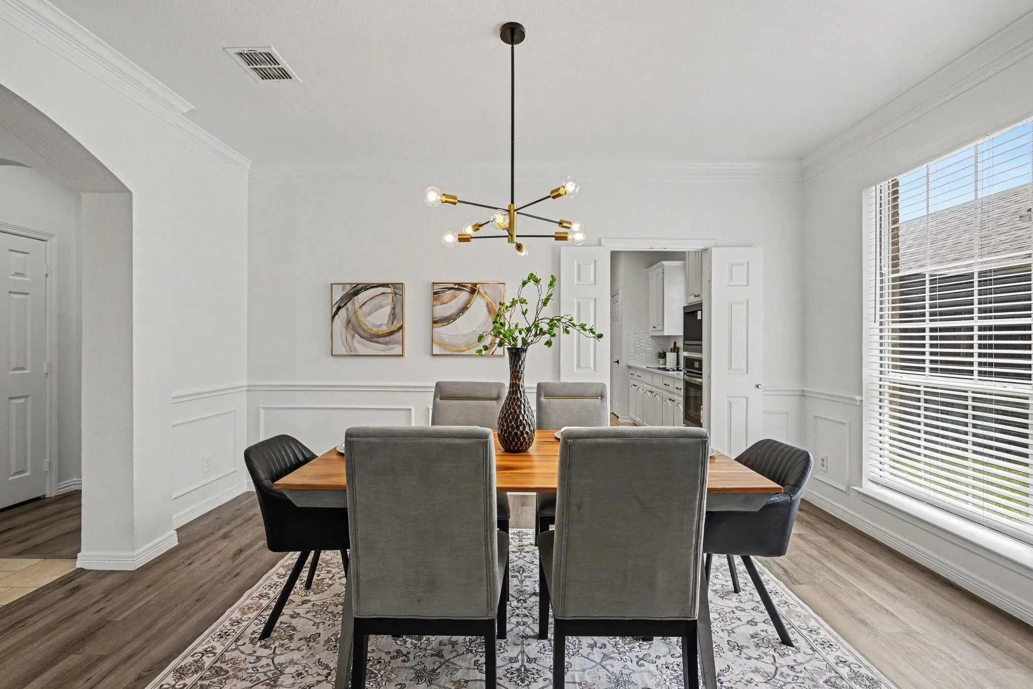 Spacious dining area featuring wood-finish flooring, wainscoting, and crown molding