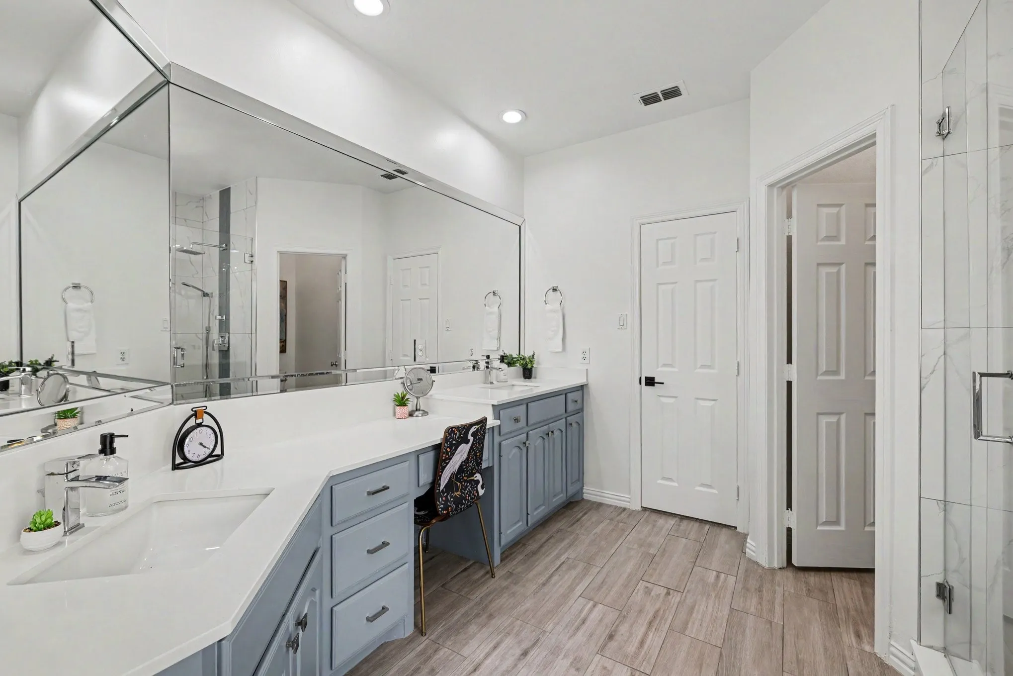 Spacious bathroom featuring an expansive vanity with double undermount sinks, light blue cabinetry, and a countertop with integrated makeup desk
