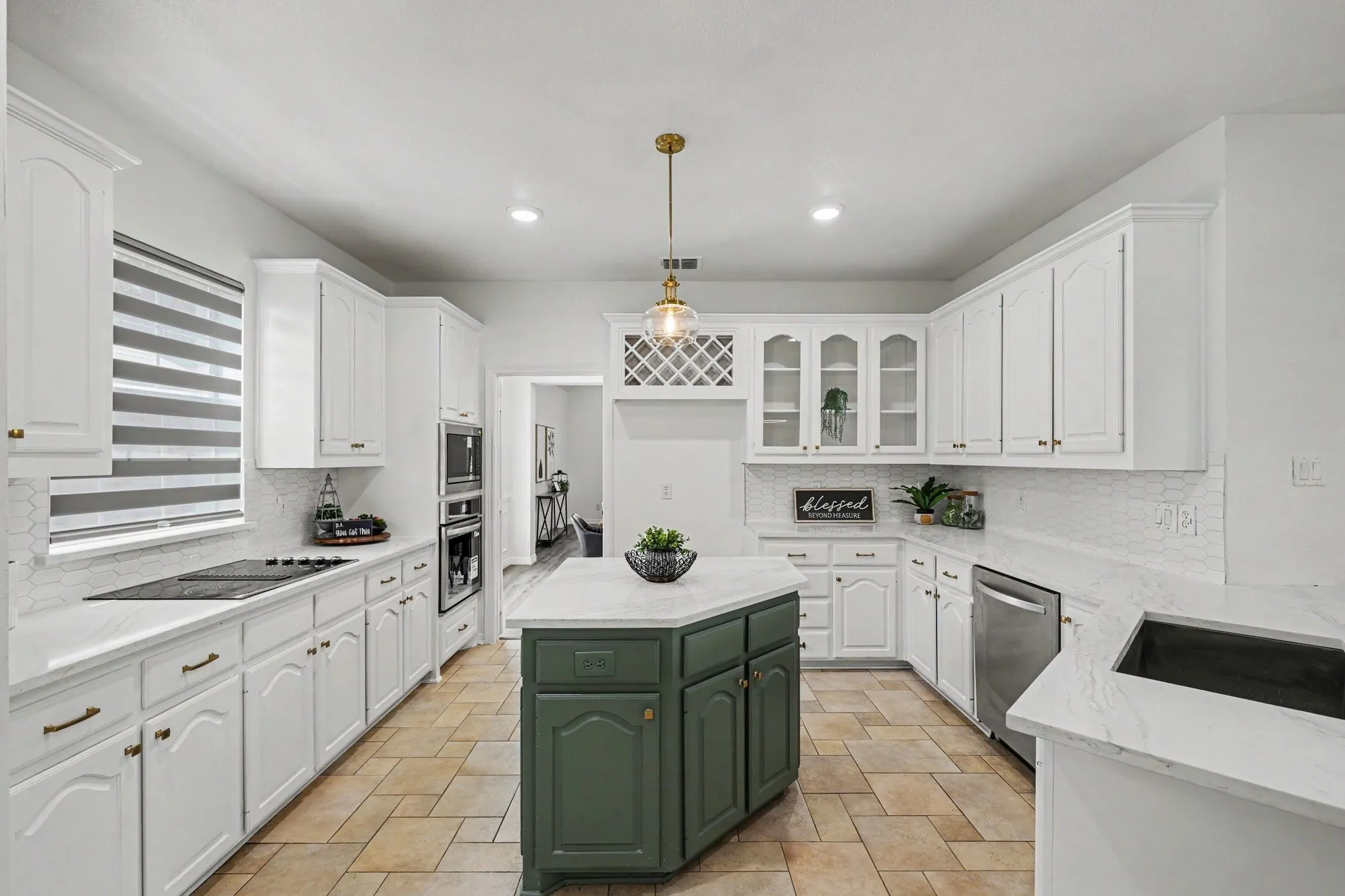 Spacious kitchen featuring white cabinetry, light-toned countertops, and a central island with a contrasting green base