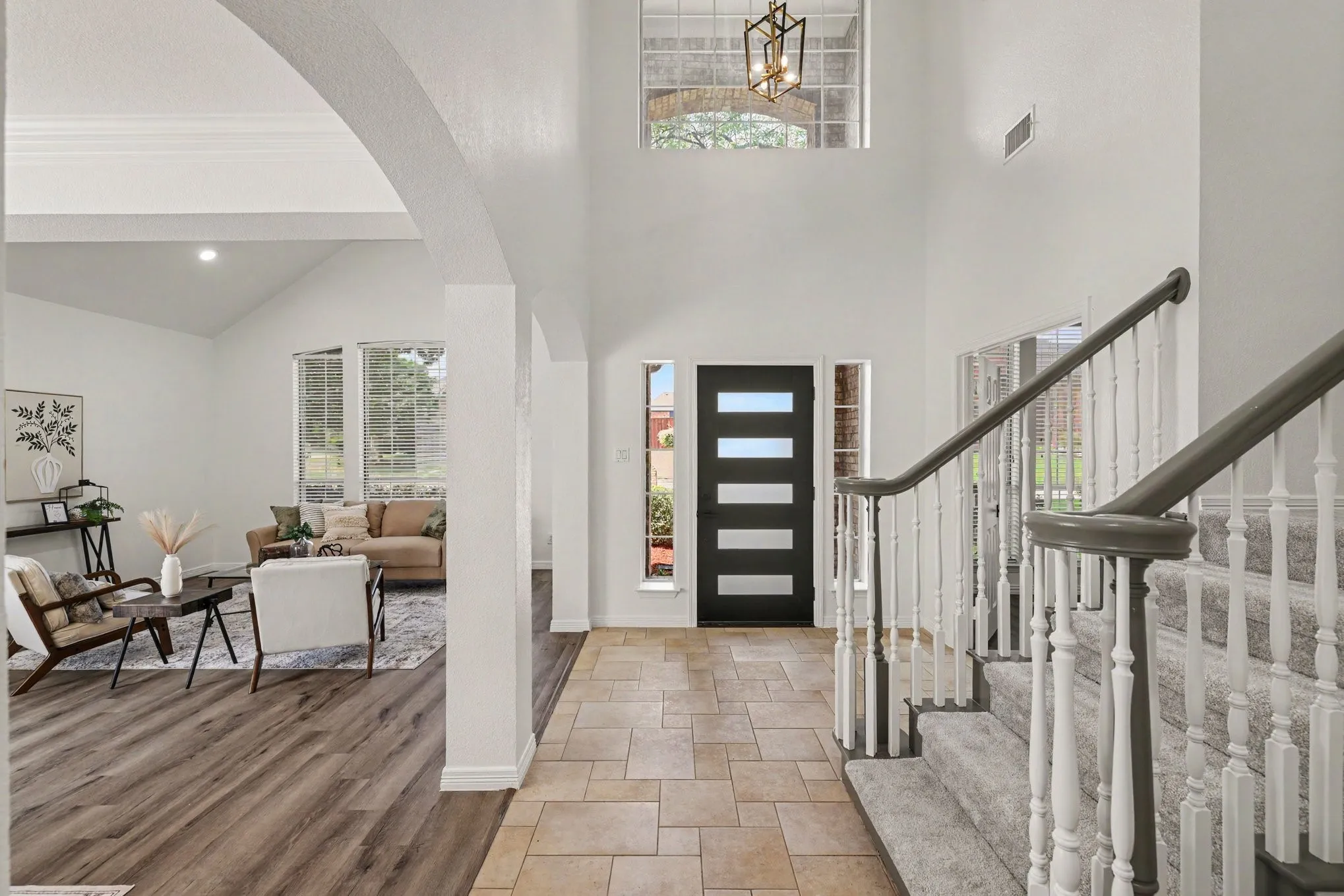 Two-story entryway with tiled flooring and a carpeted staircase featuring white balusters and gray handrails