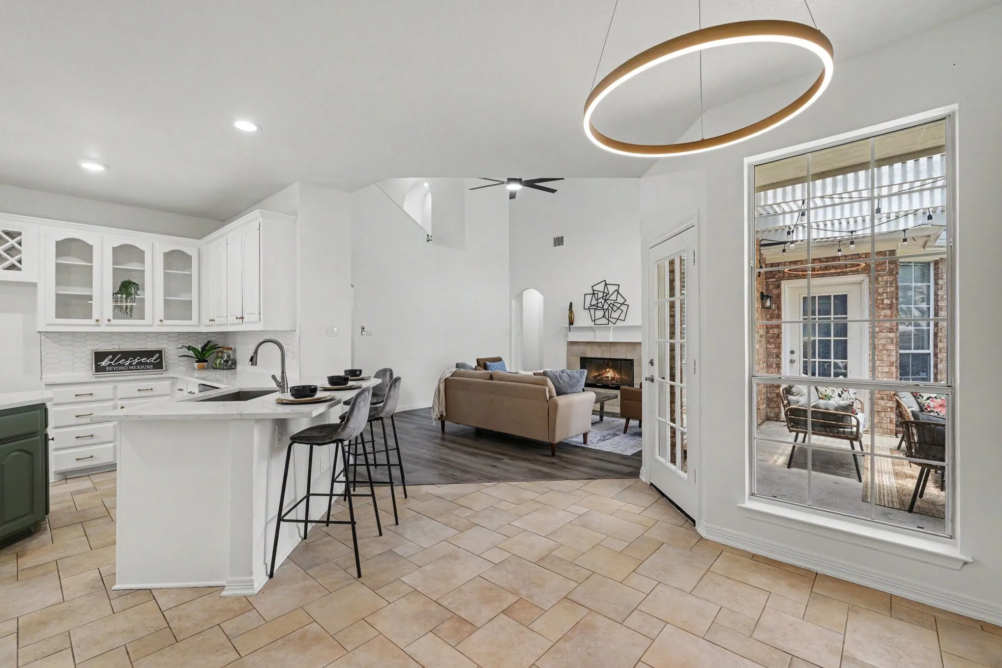 Kitchen featuring white shaker cabinetry, an island with seating, pendant lighting, and tile flooring