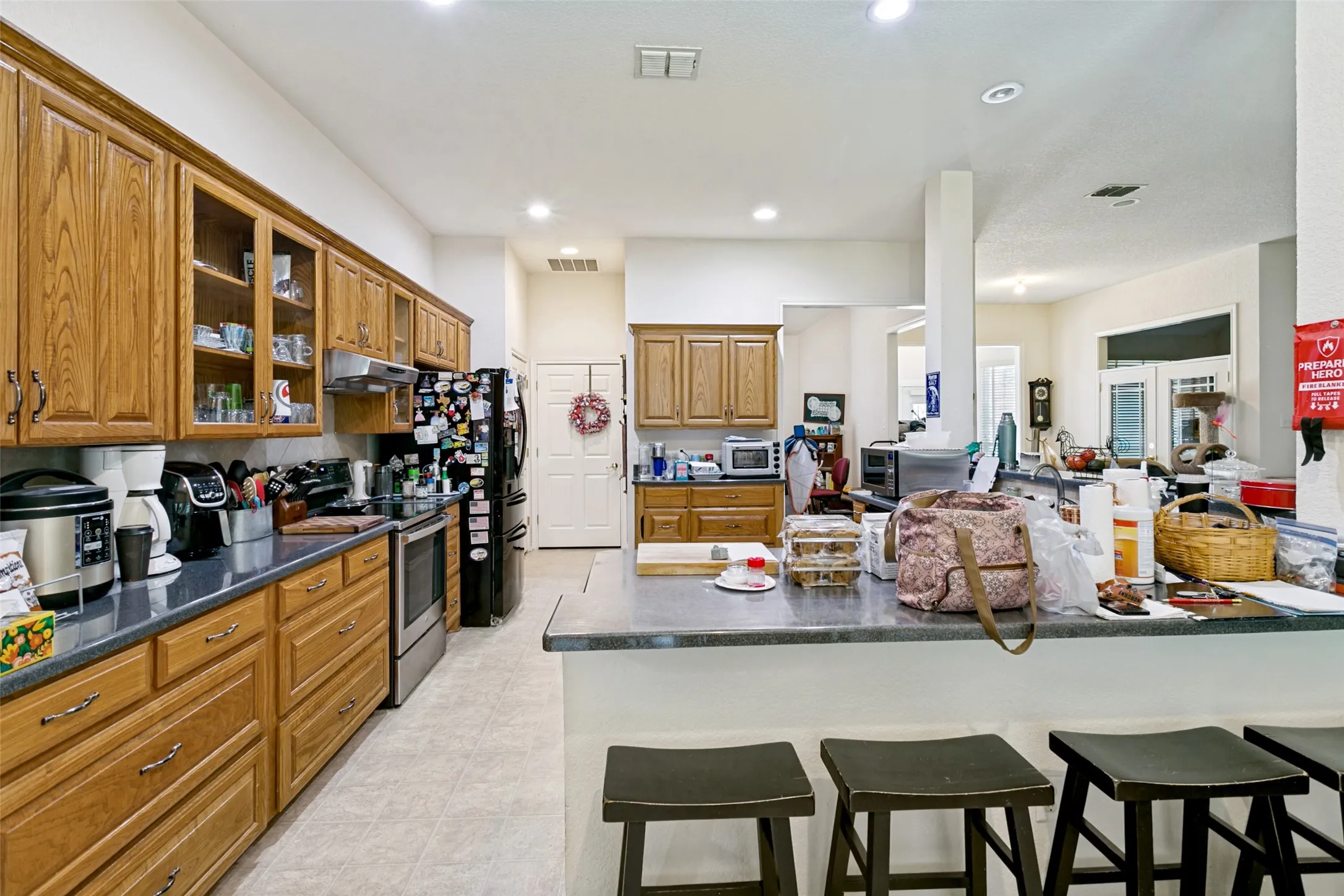 Kitchen featuring wood cabinetry, dark countertops, a built-in stainless steel range, and recessed lighting