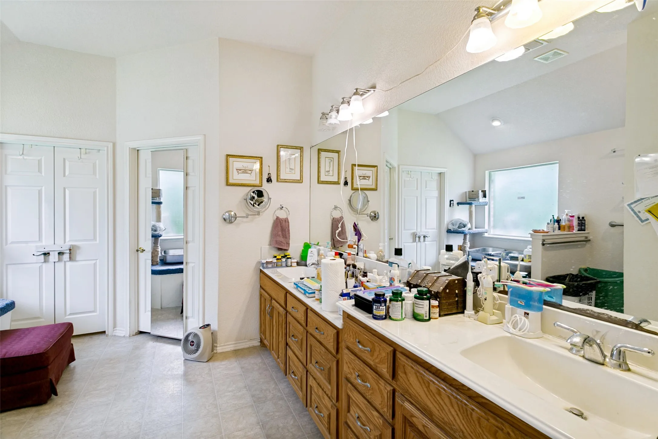 Dual sink vanity featuring wood cabinetry and an expansive mirror with overhead lighting