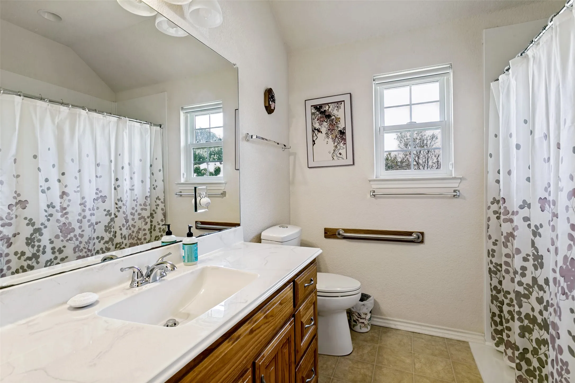 Bathroom featuring a single vanity with a white countertop and integrated sink, chrome faucet, and wood-finish cabinetry