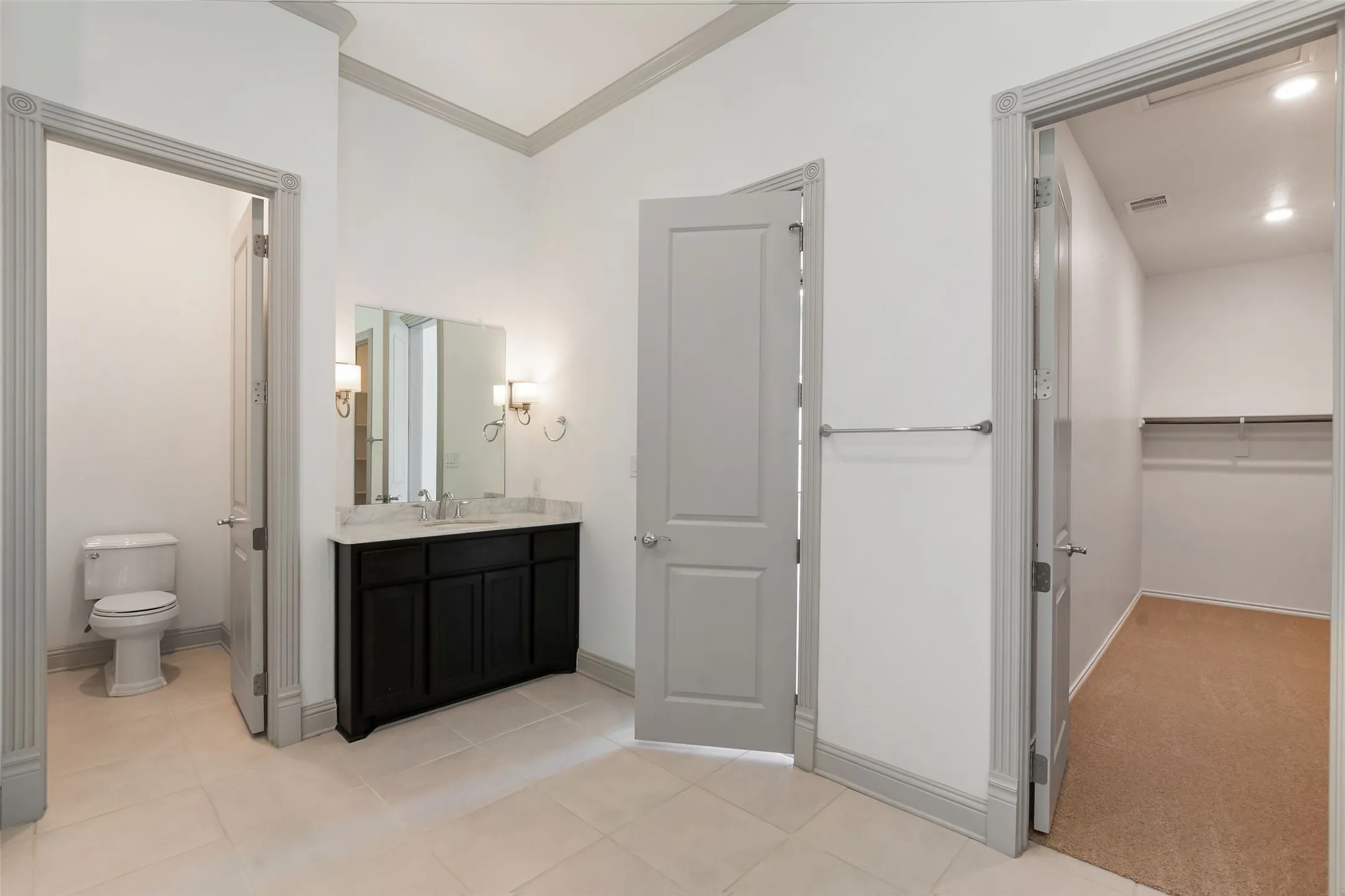 Bathroom vanity featuring a dark wood-finish cabinet, light countertop, and dual wall sconces