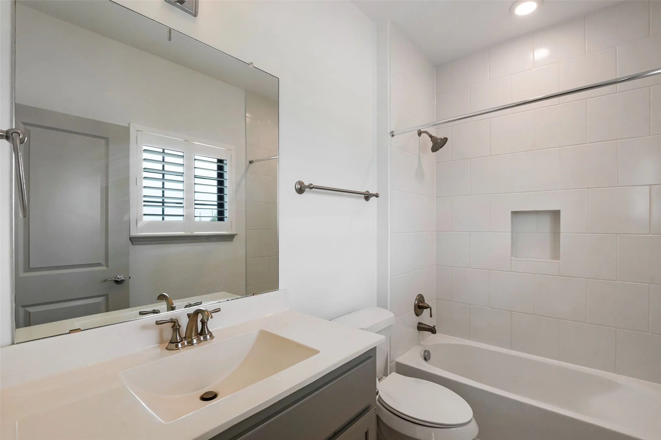 Bathroom featuring a white subway tile shower, built-in shower niche, and a vanity with a rectangular undermount sink
