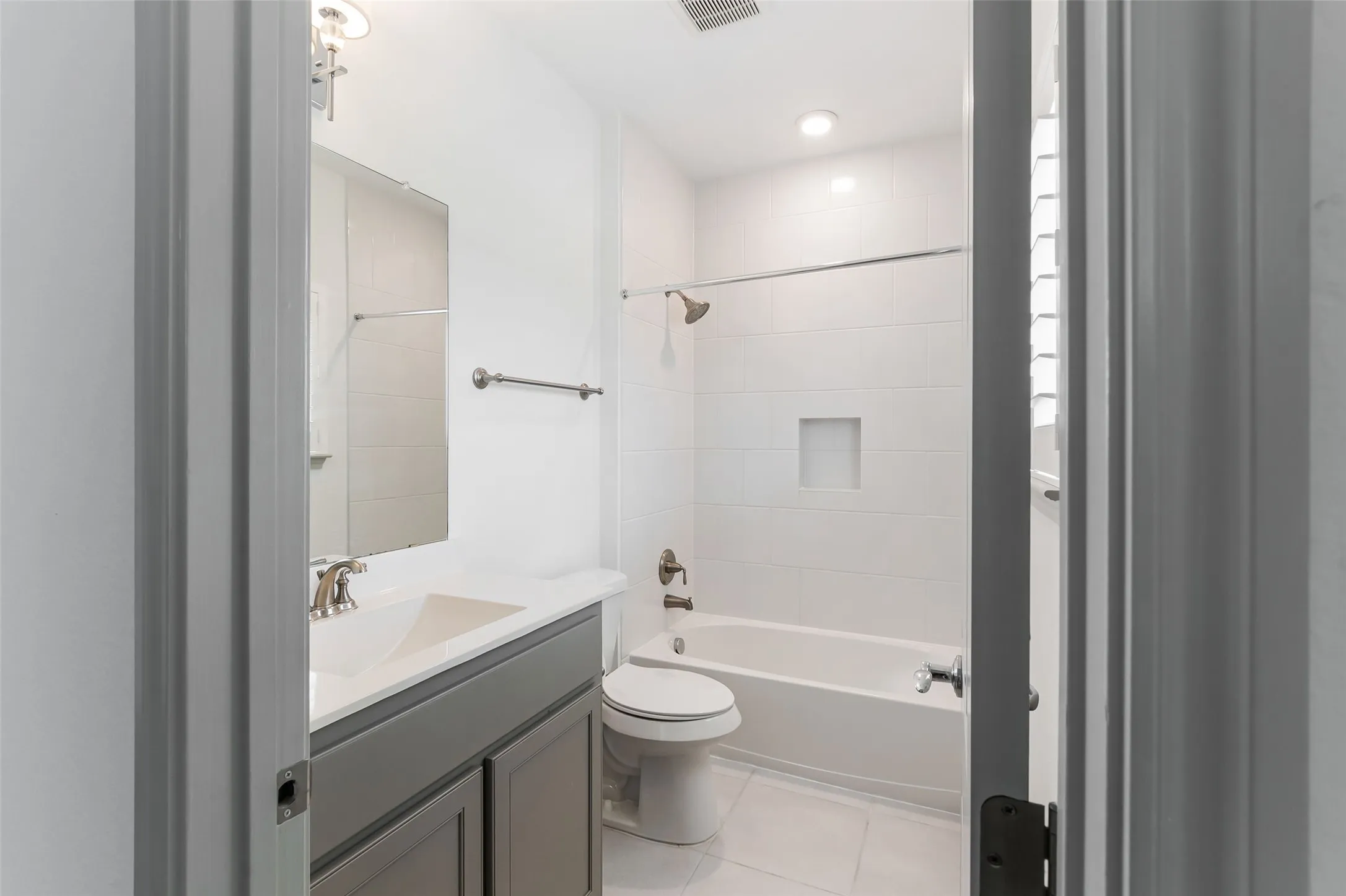 Full bathroom featuring a single vanity with grey cabinetry, a white countertop, and an undermount sink