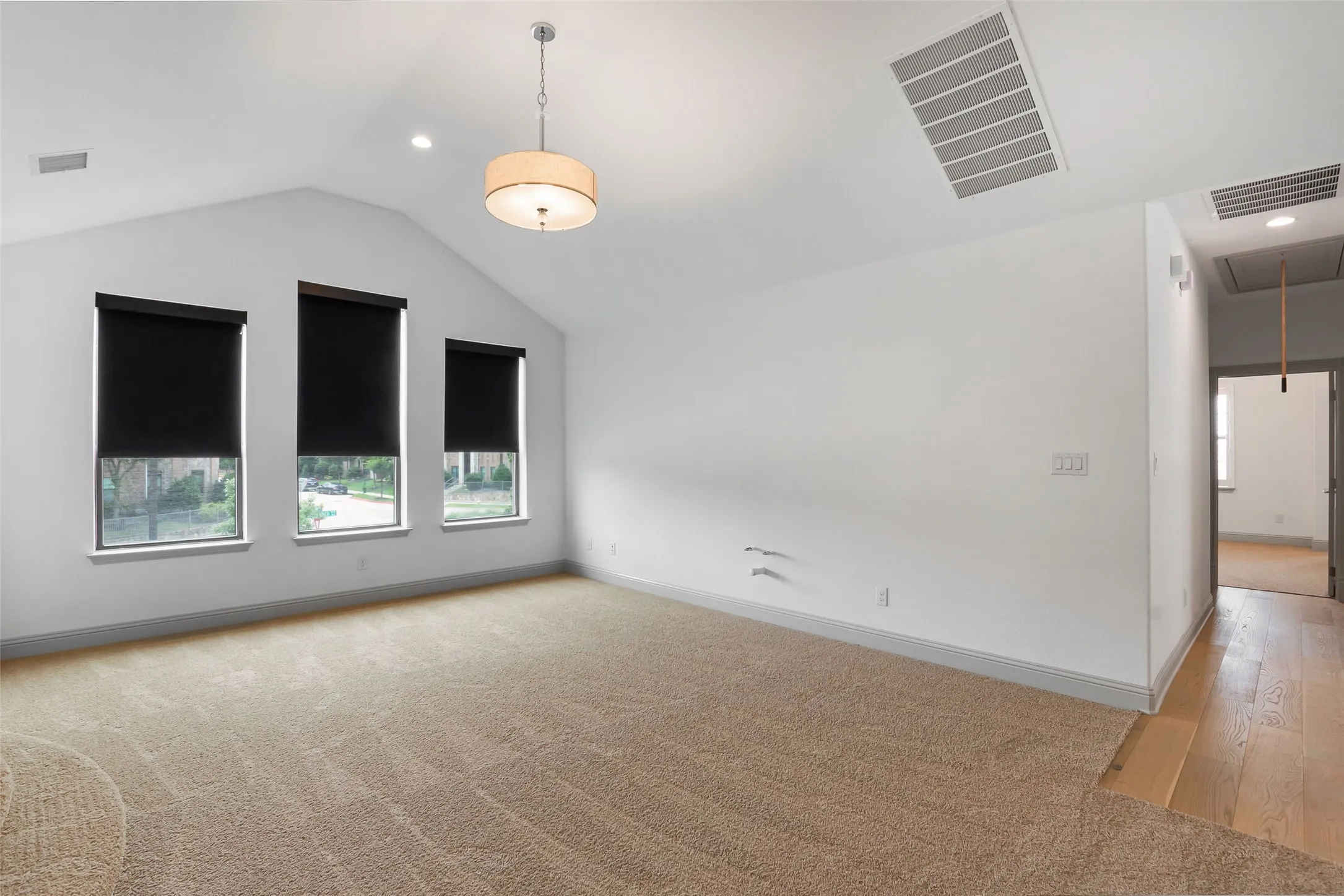 Spacious room with a vaulted ceiling, three large windows, a drum pendant light fixture, and recessed lighting