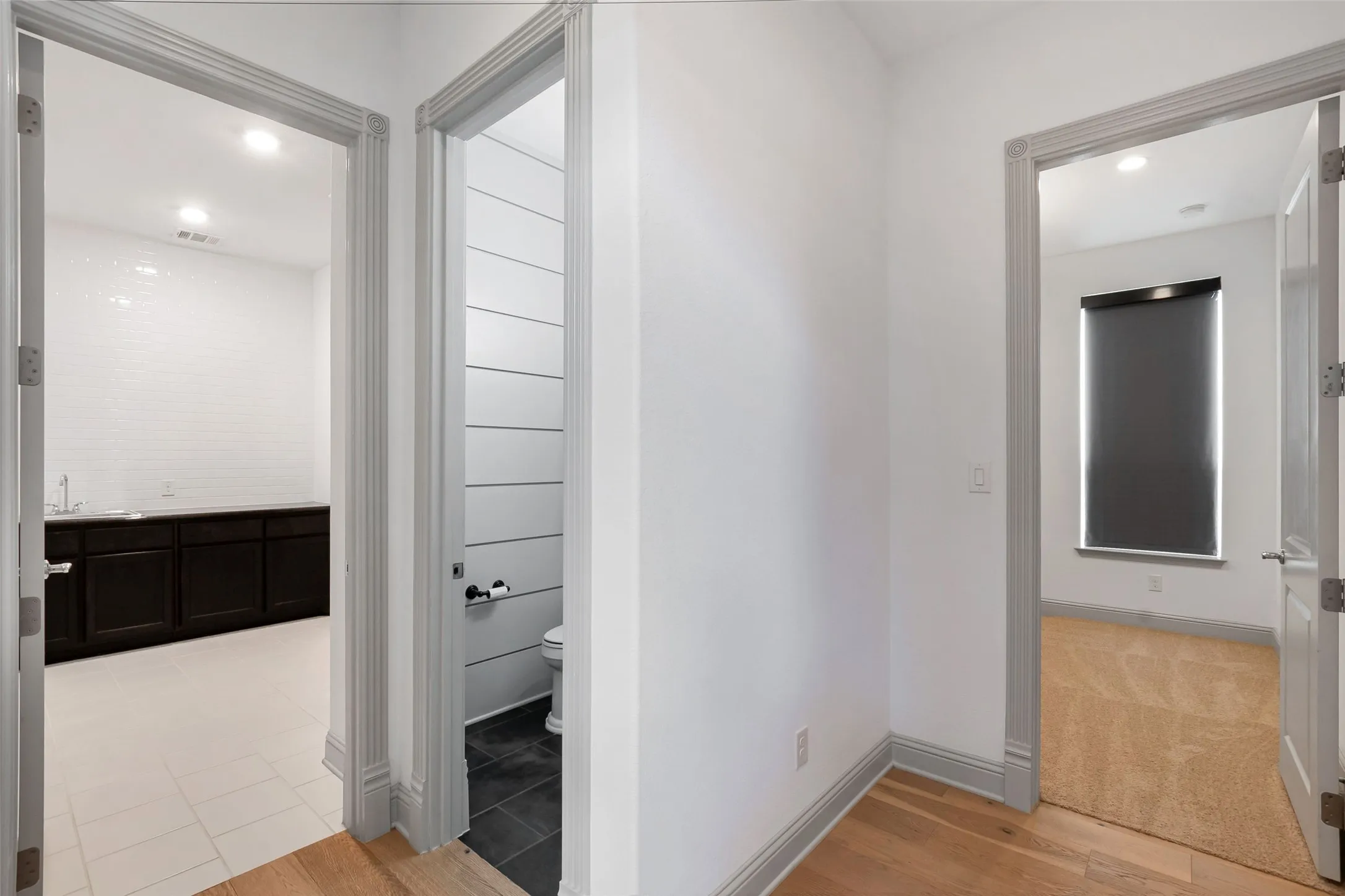 Hallway featuring wood-finish flooring, white walls, and elegant gray trim