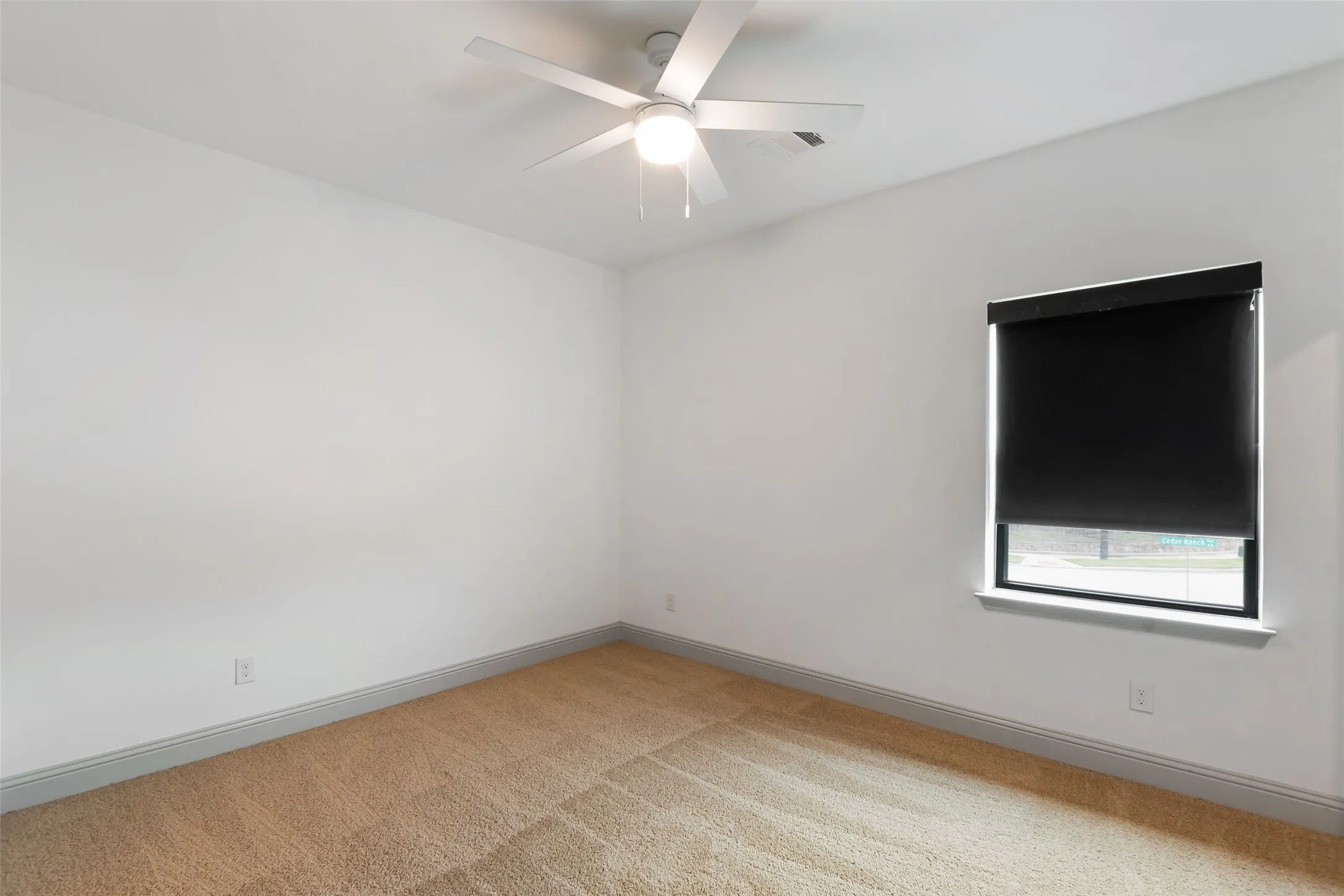 Spacious room featuring neutral carpeting, white walls, and a modern ceiling fan with integrated lighting