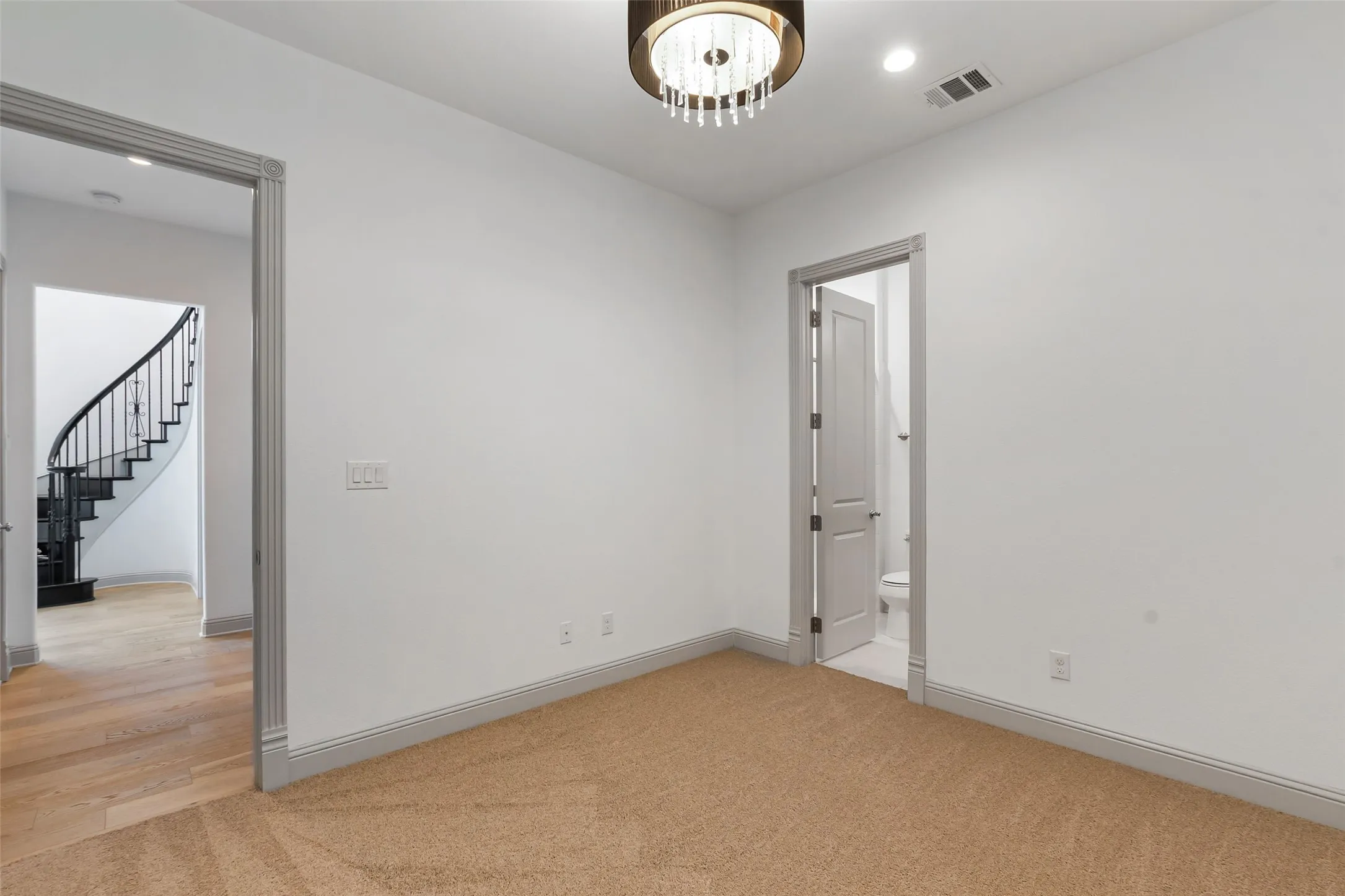 Carpeted interior room with white walls, gray trim, and a decorative ceiling light fixture